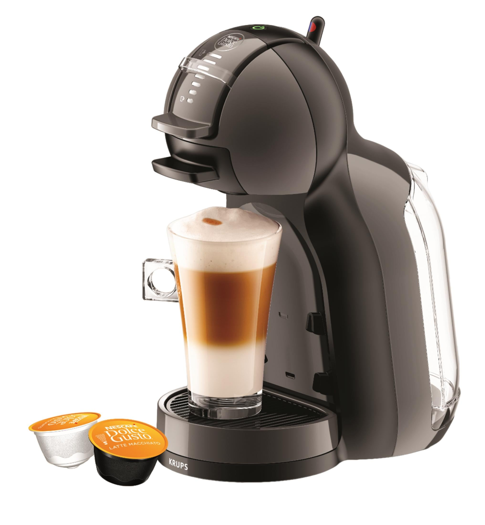 Eine schwarze Kaffeemaschine mit einem Glas Latte Macchiato und zwei Kaffeekapseln daneben.