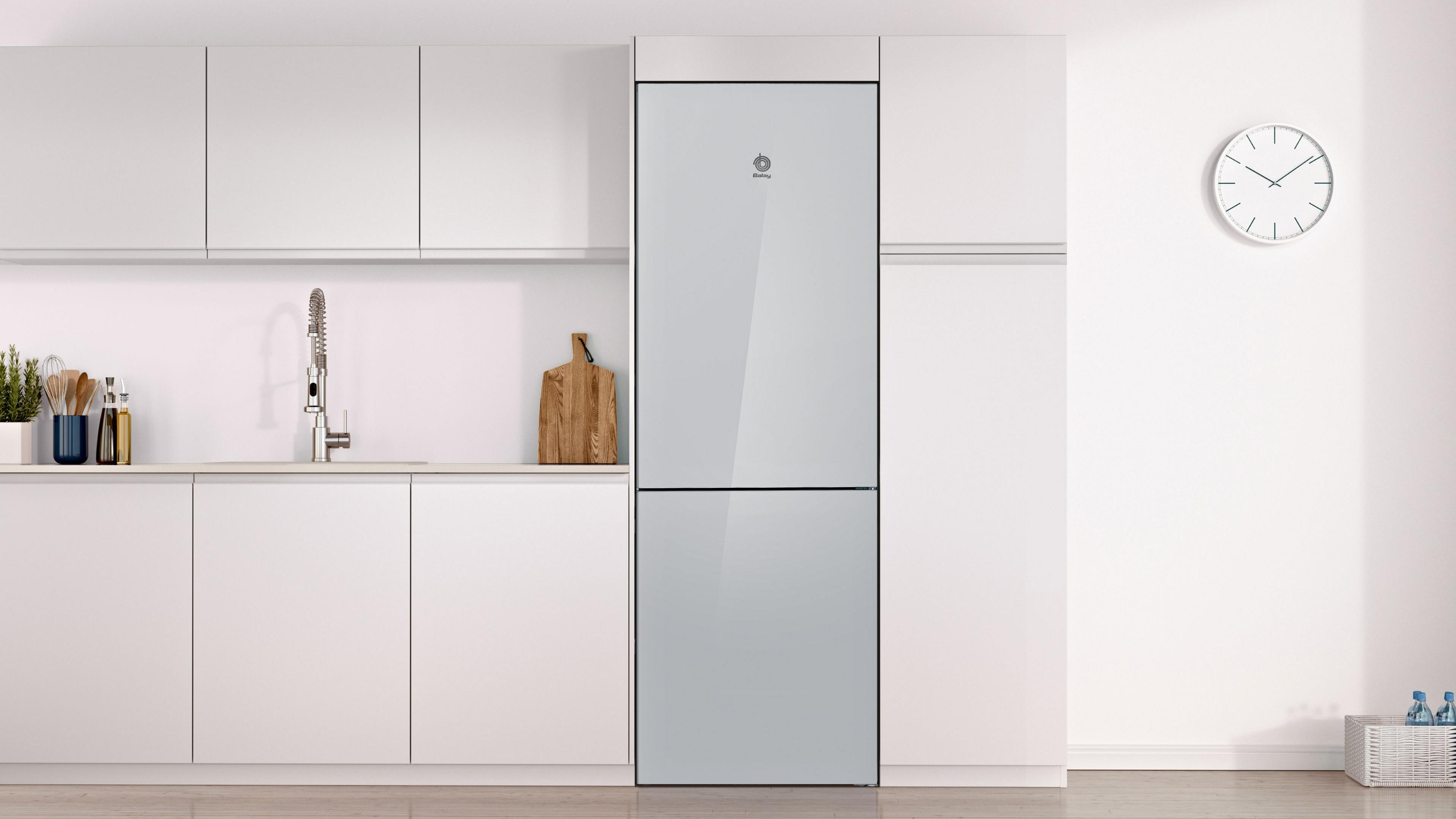 Una cocina moderna con gabinetes blancos, refrigerador, grifo y taburete.