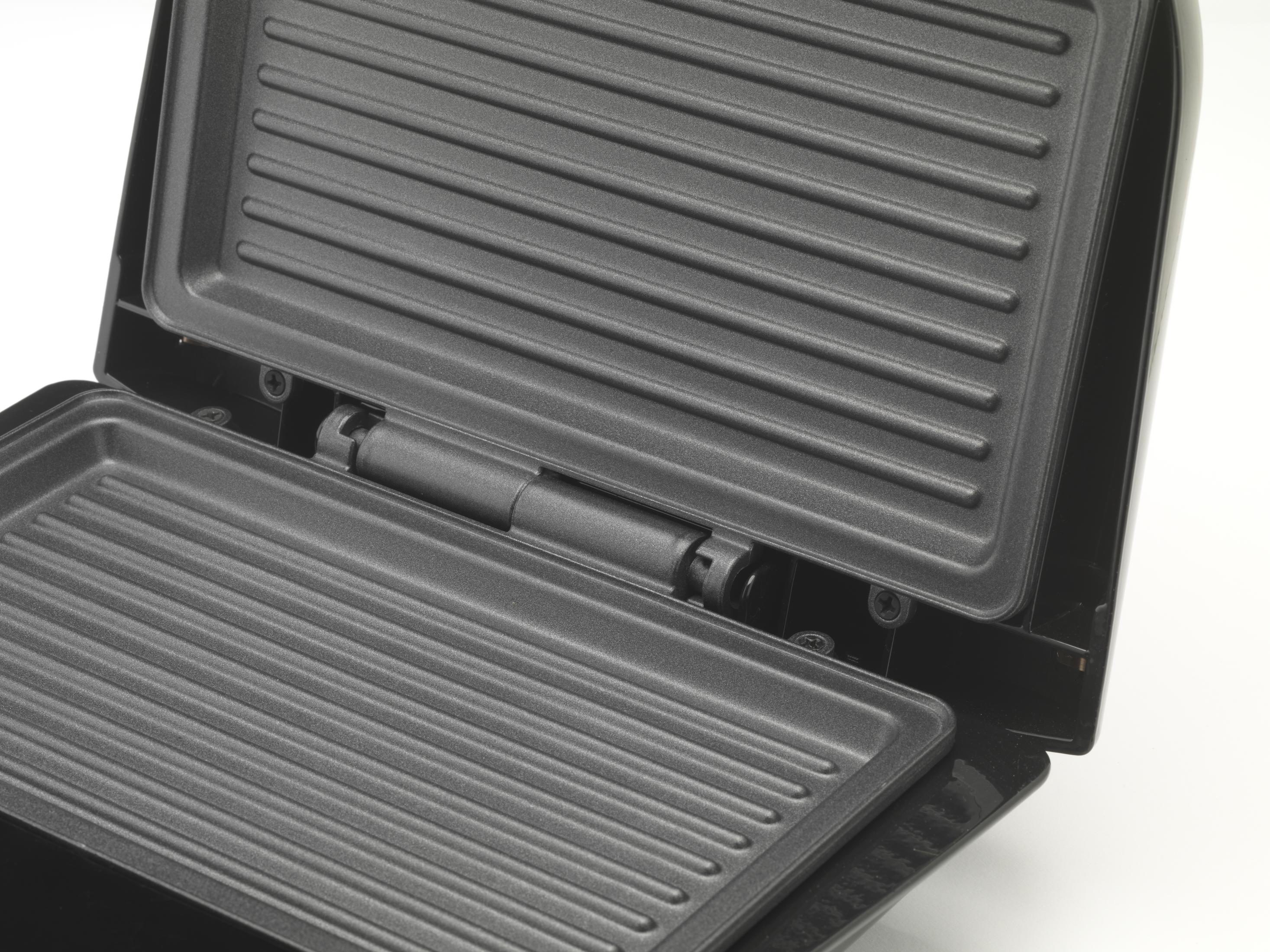 Ein geöffneter, schwarzer Kontaktgrill mit geriffelten Heizplatten auf weißem Hintergrund.
