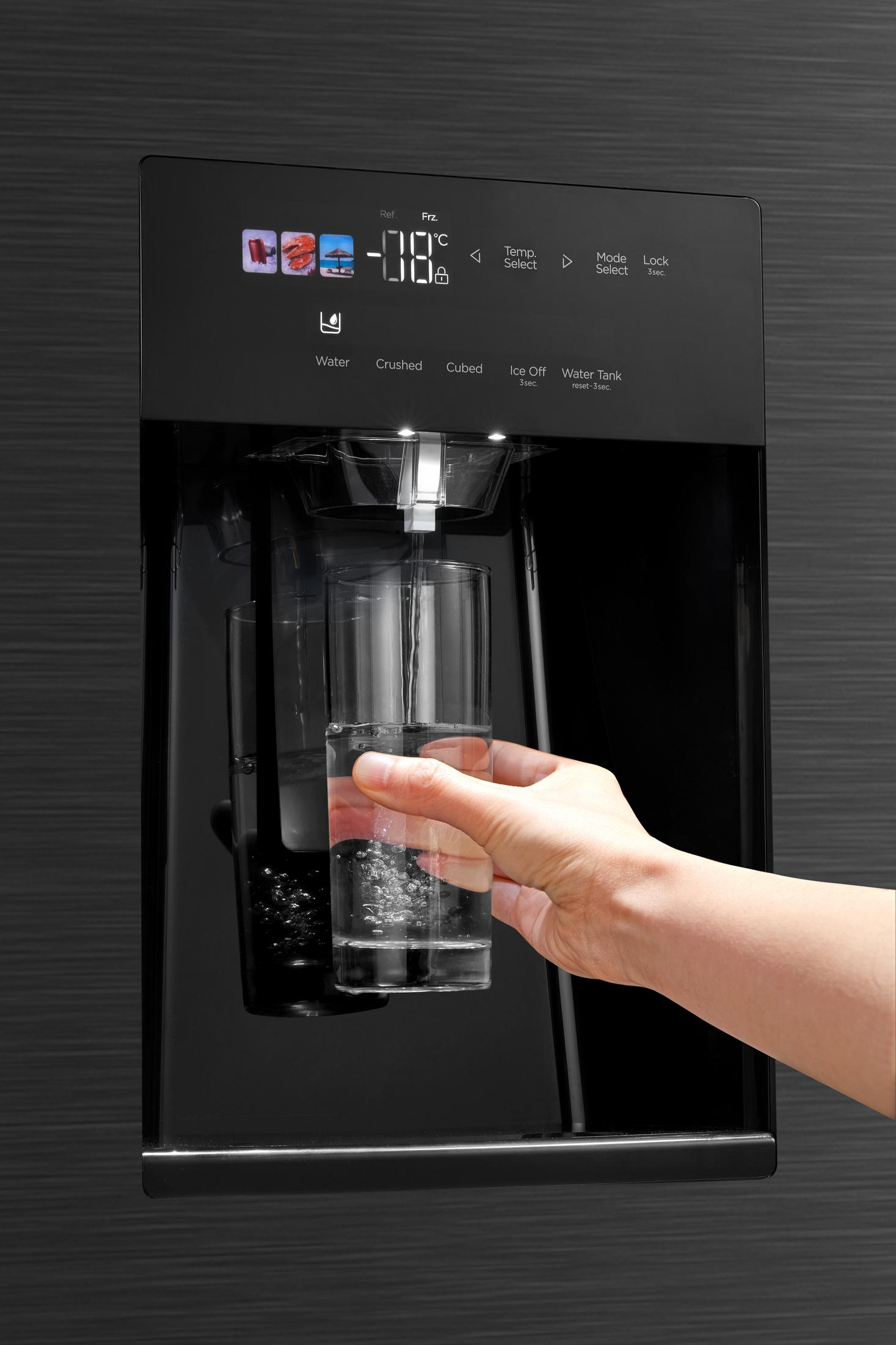 Eine Hand füllt ein Glas mit Wasser aus einem Kühlschrank-Wasserspender.