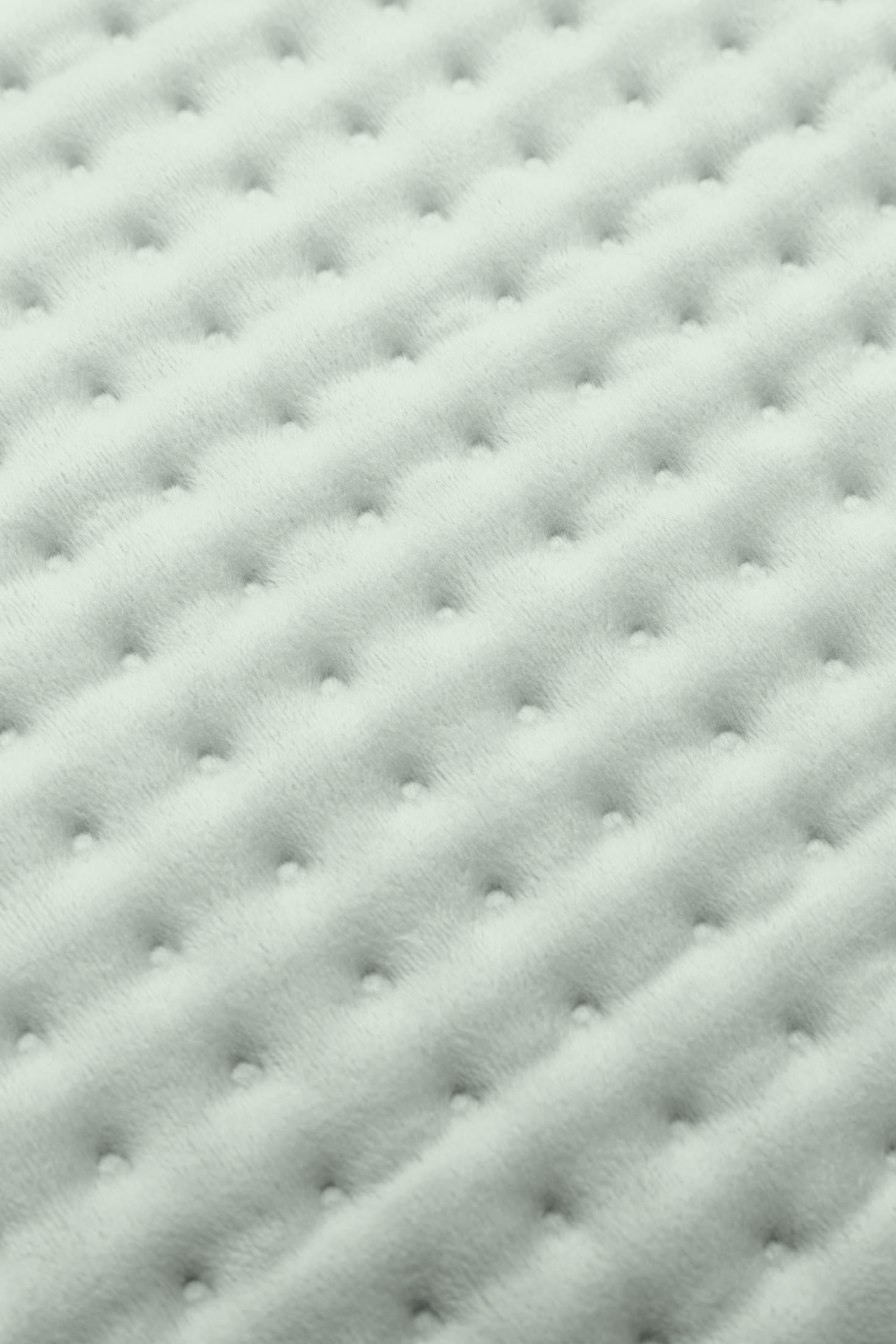 Primer plano de una manta acolchada gris claro con mechones simétricos.