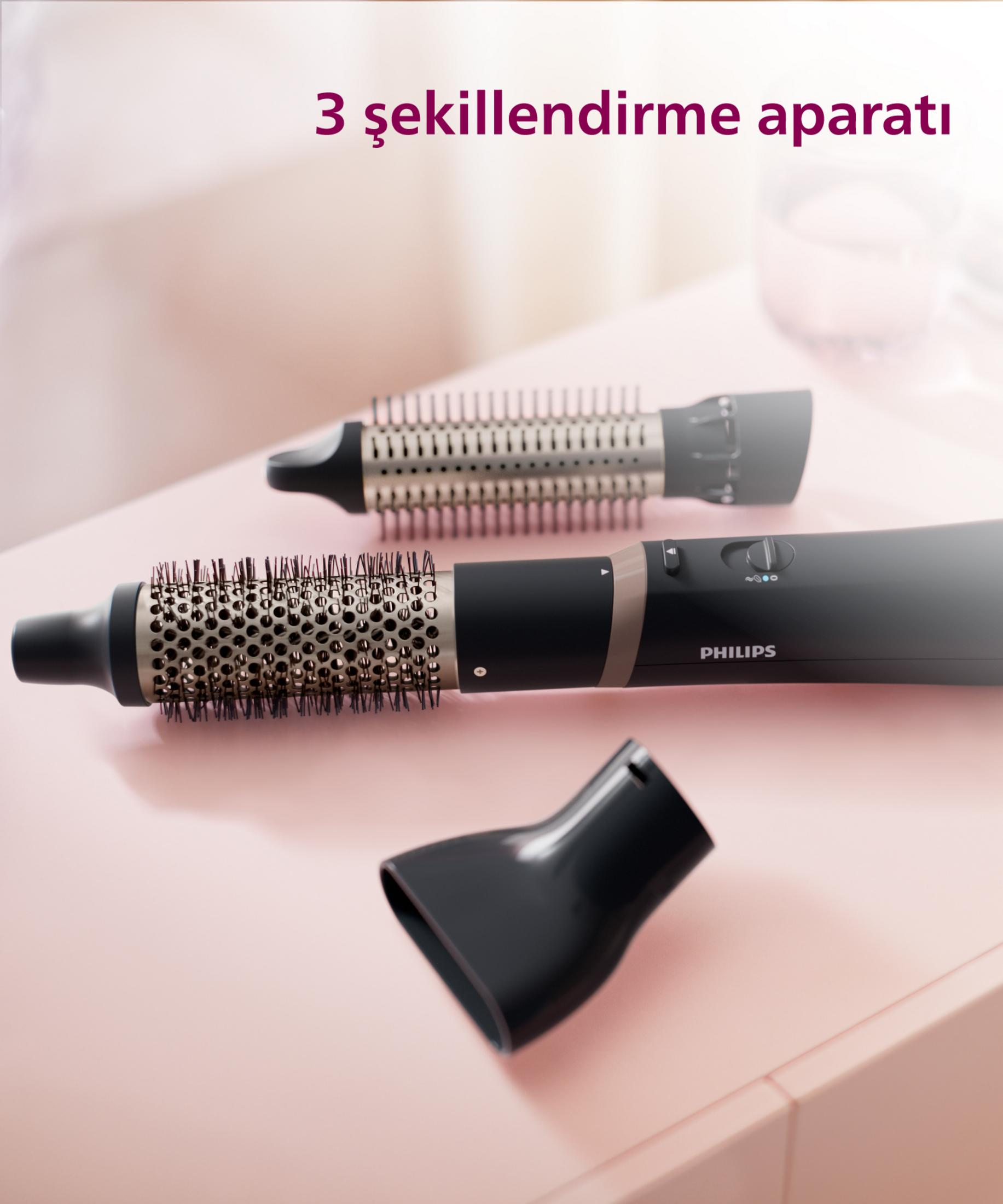 Styling per capelli Philips con tre accessori su superficie rosa.