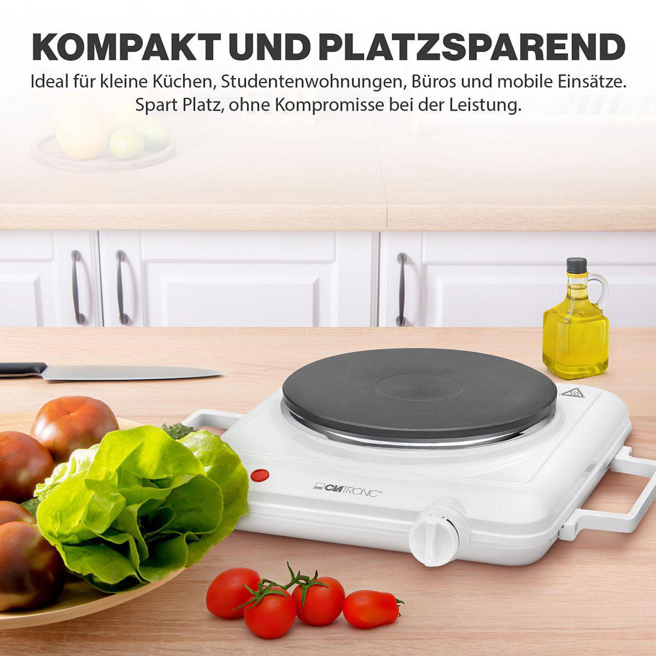 Ein weißer Tischkochherd mit Kochfeld, daneben ein Salat, Tomaten und Öl.