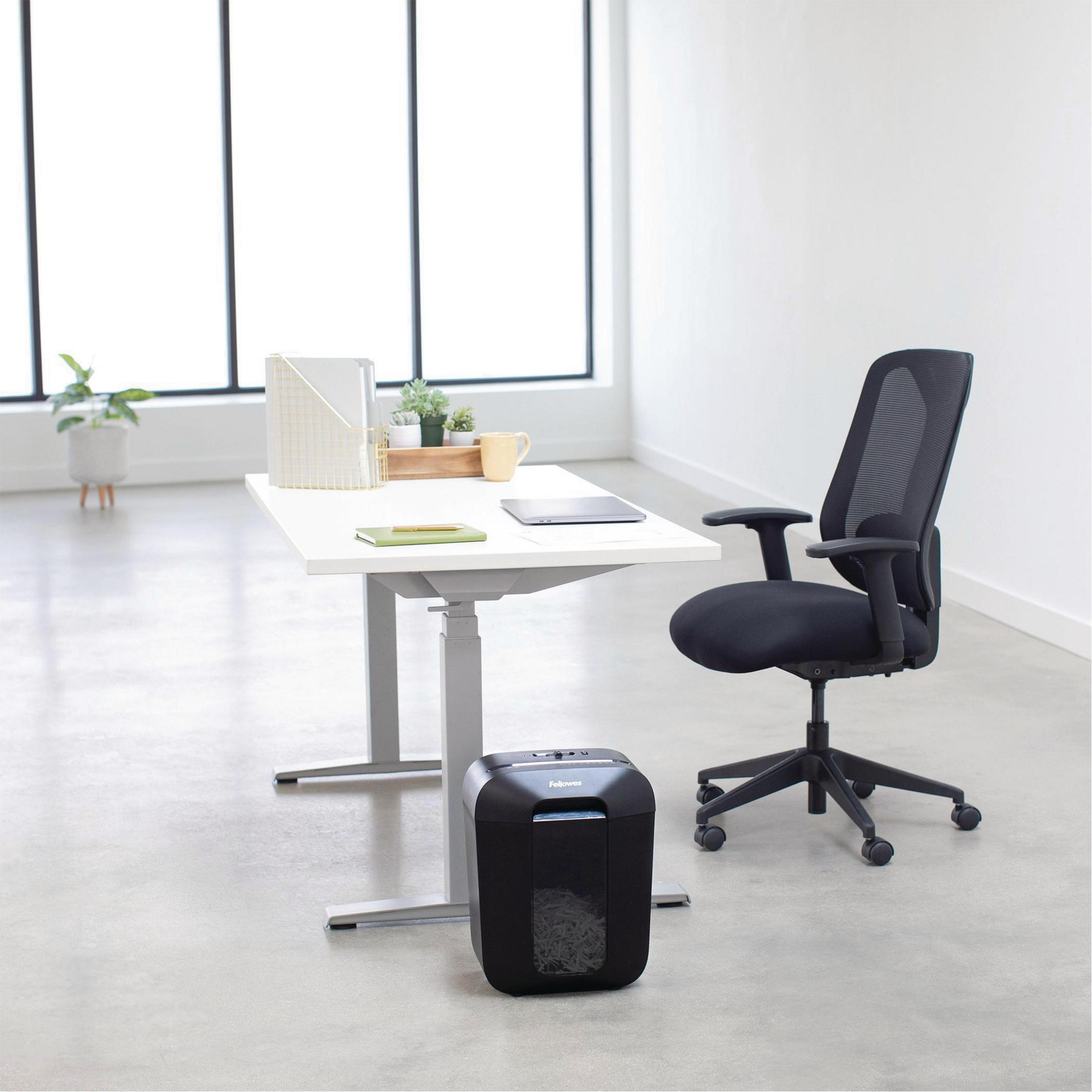 Un bureau avec un bureau, une chaise et une déchiqueteuse.