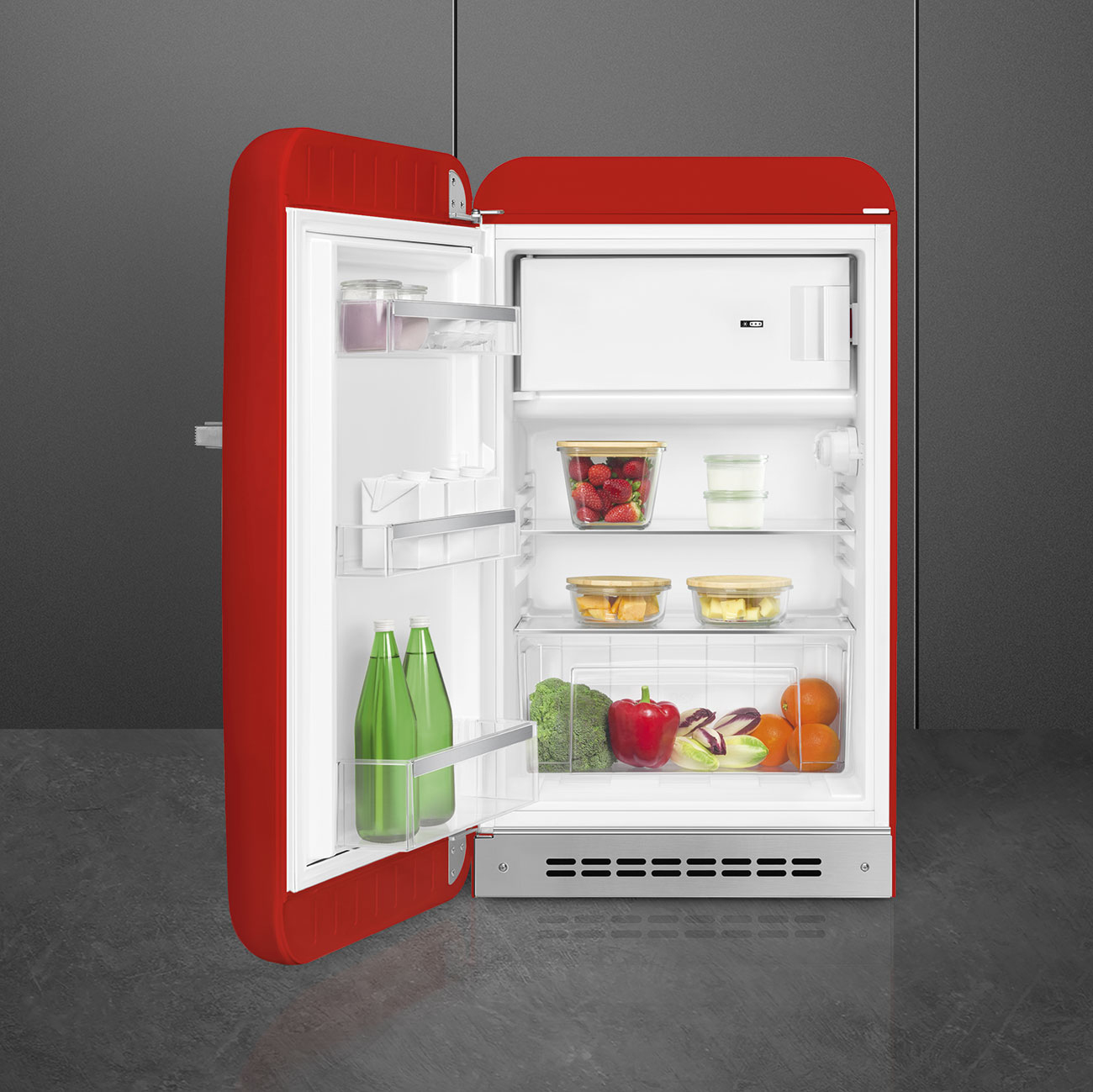 Un frigorifero rosso aperto espone cibi come bacche, verdure e bottiglie.