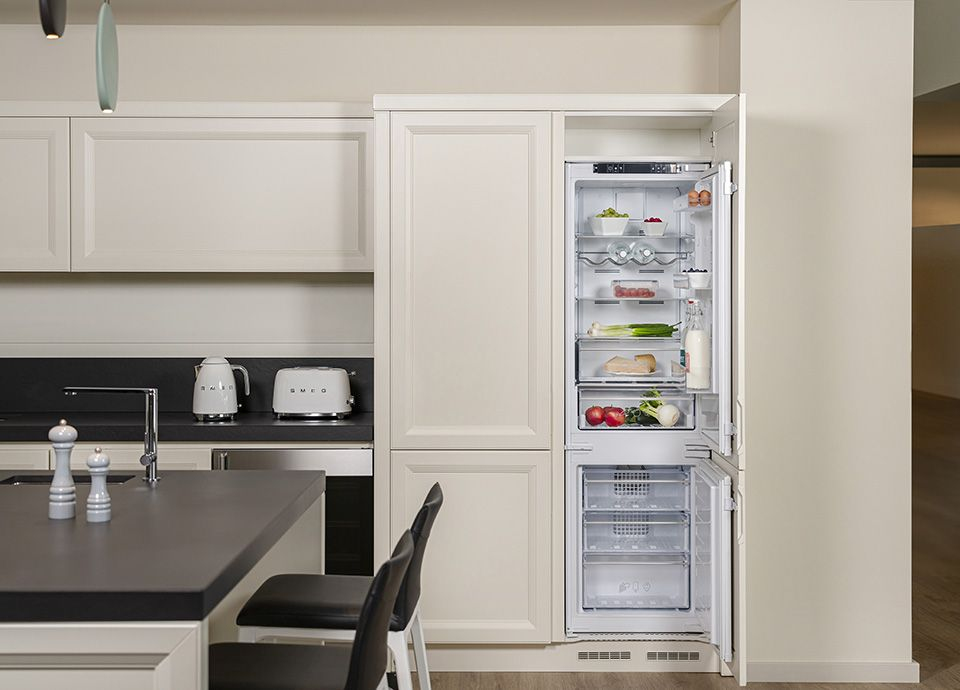 Une cuisine moderne avec réfrigérateur ouvert garni, grille-pain et bouilloire.