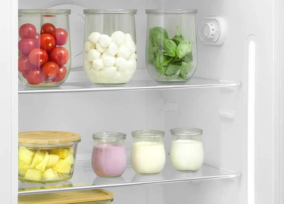 Bocaux de tomates, mozzarella, basilic, ananas et yaourt dans un réfrigérateur.