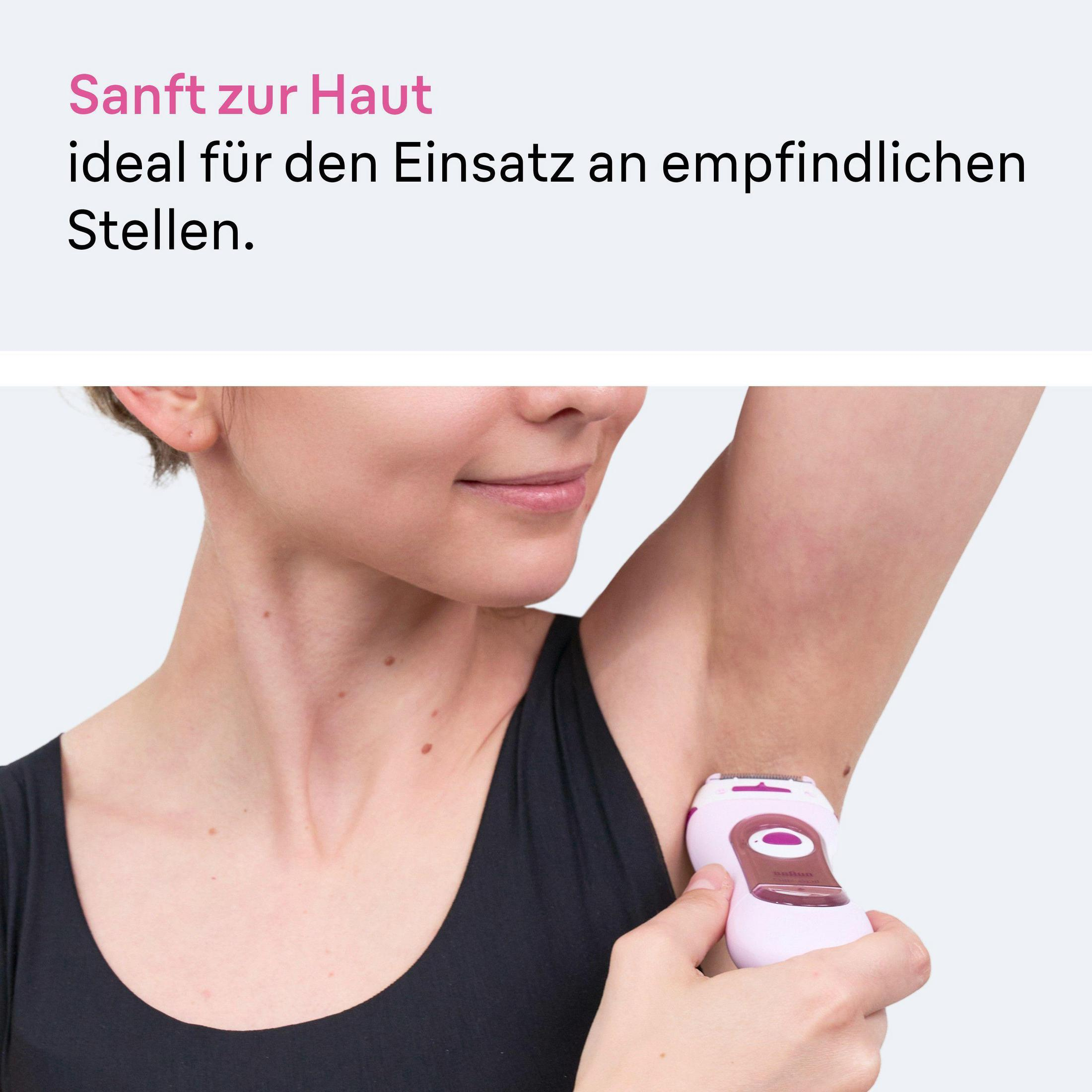 Una mujer usa un depilador rosa debajo del brazo.