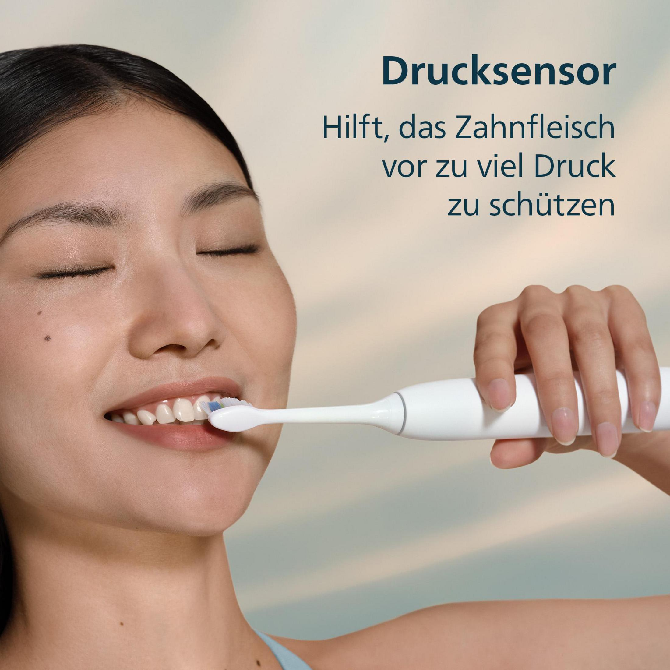 Eine Frau putzt mit einer elektrischen Zahnbürste die Zähne.