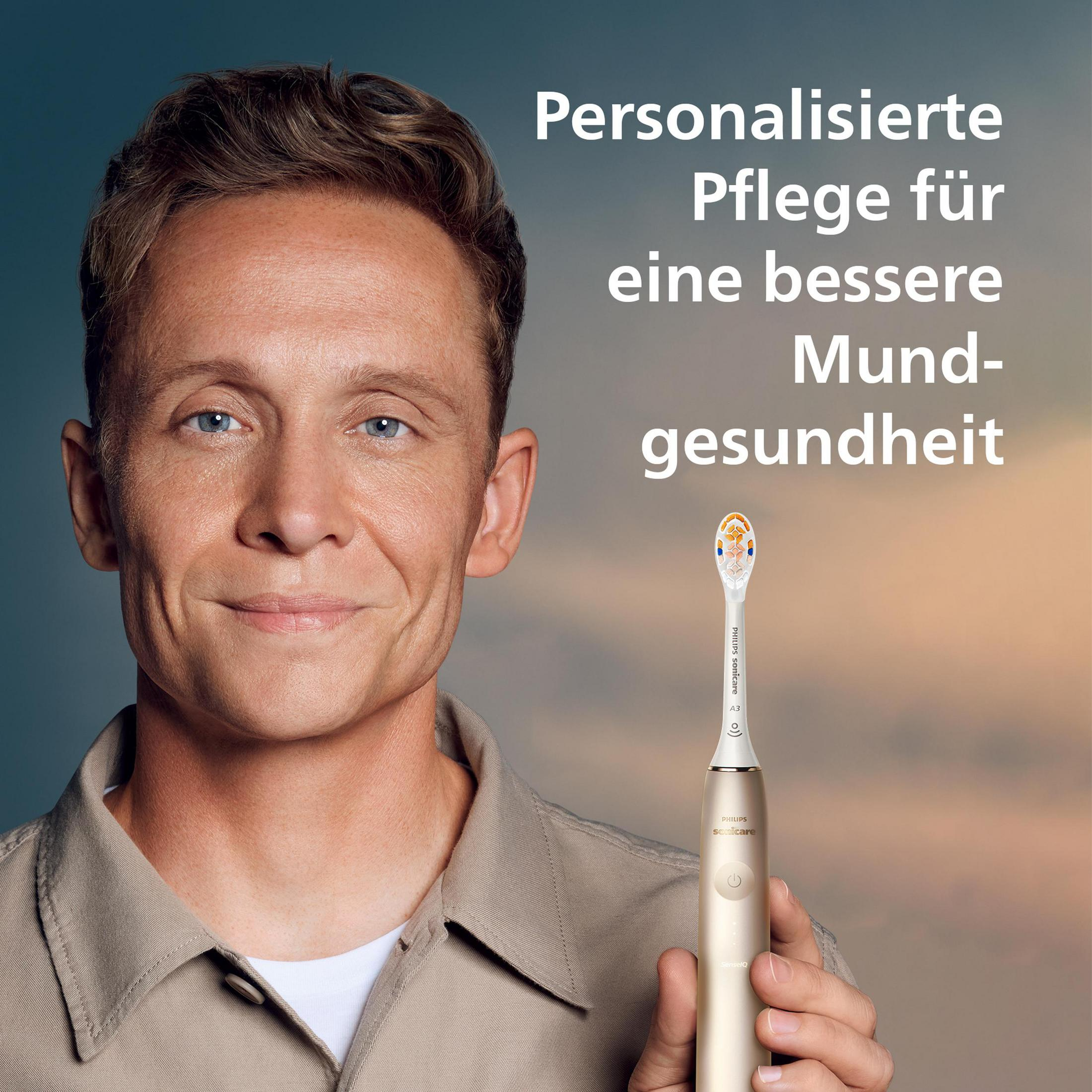 Uomo tiene spazzolino sonico dorato con logo Philips. Cura personalizzata.