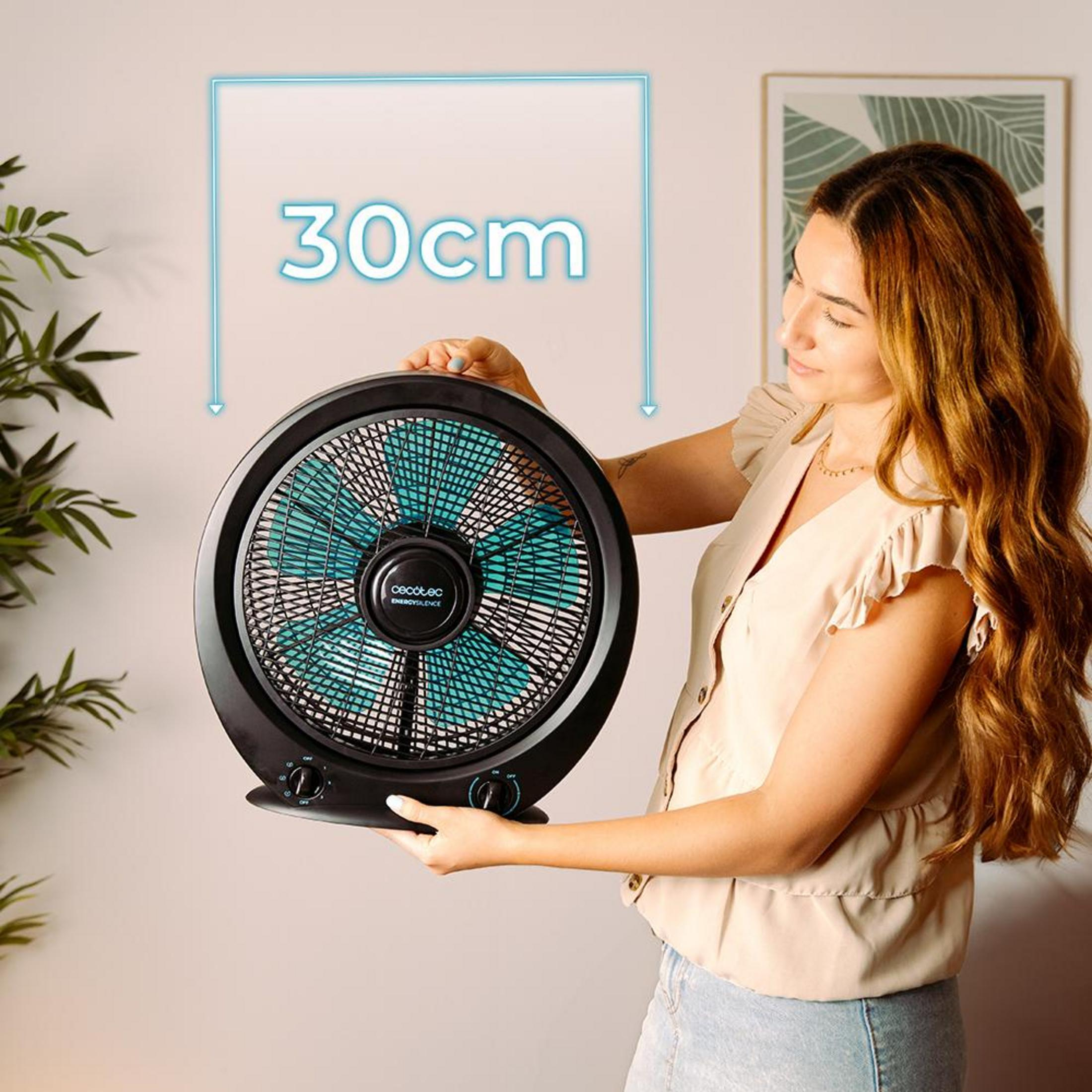 Una mujer sostiene un ventilador negro con aspas turquesas. "30cm" se muestra encima.