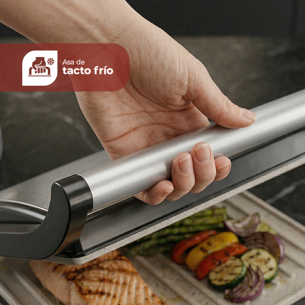 Mano sujetando asa fría sobre salmón, espárragos, calabacín, pimientos y cebolla.
