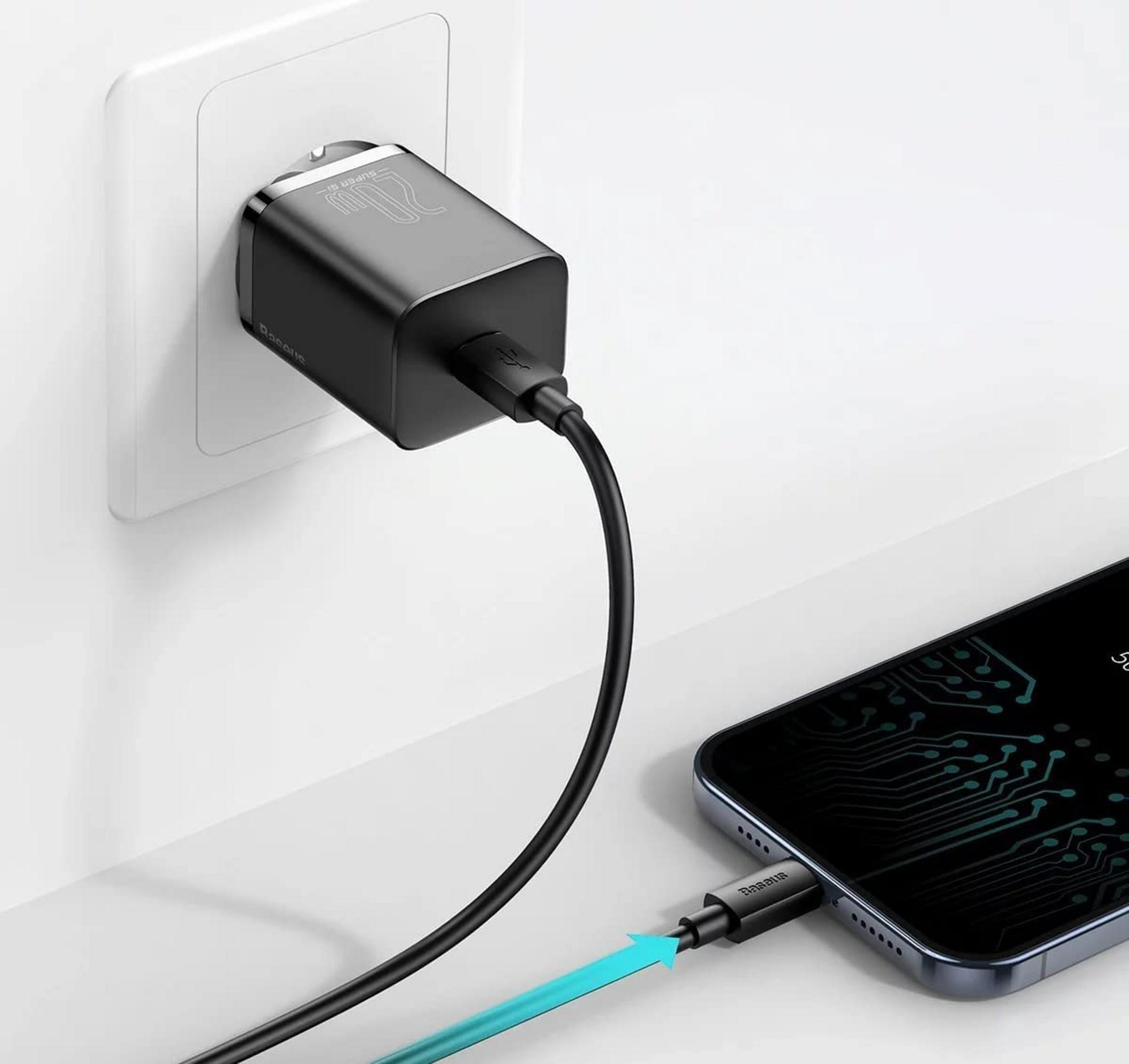 Ein schwarzes Ladegerät in einer weißen Steckdose, das ein Smartphone lädt.