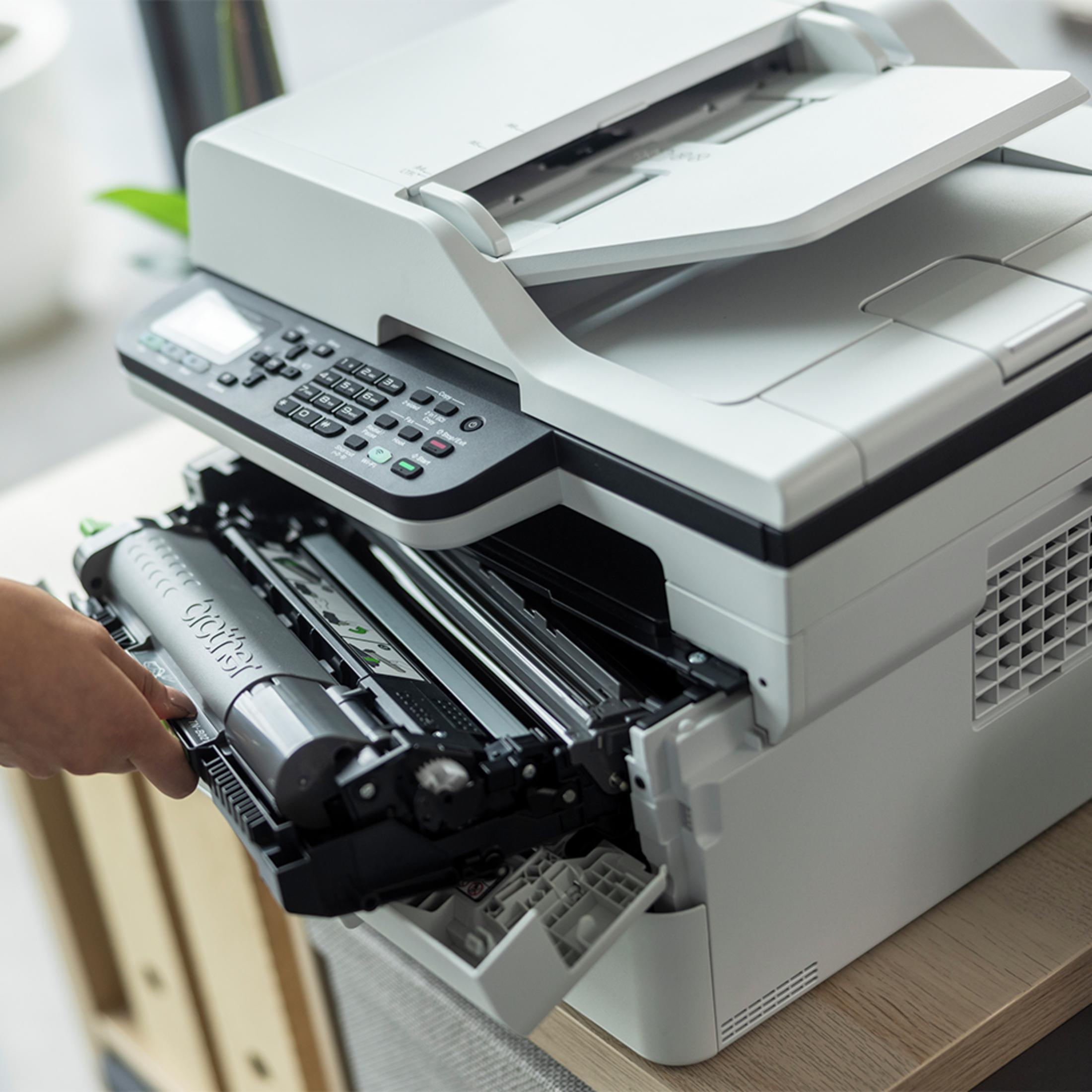 Una mano sostituisce una cartuccia toner Brother grigia in una stampante multifunzione.