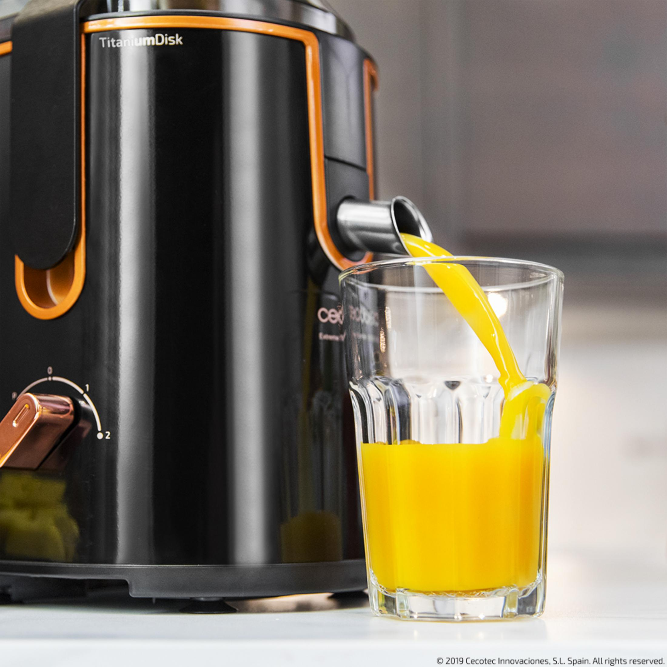 Orangensaft fließt aus einem Entsafter in ein Glas.