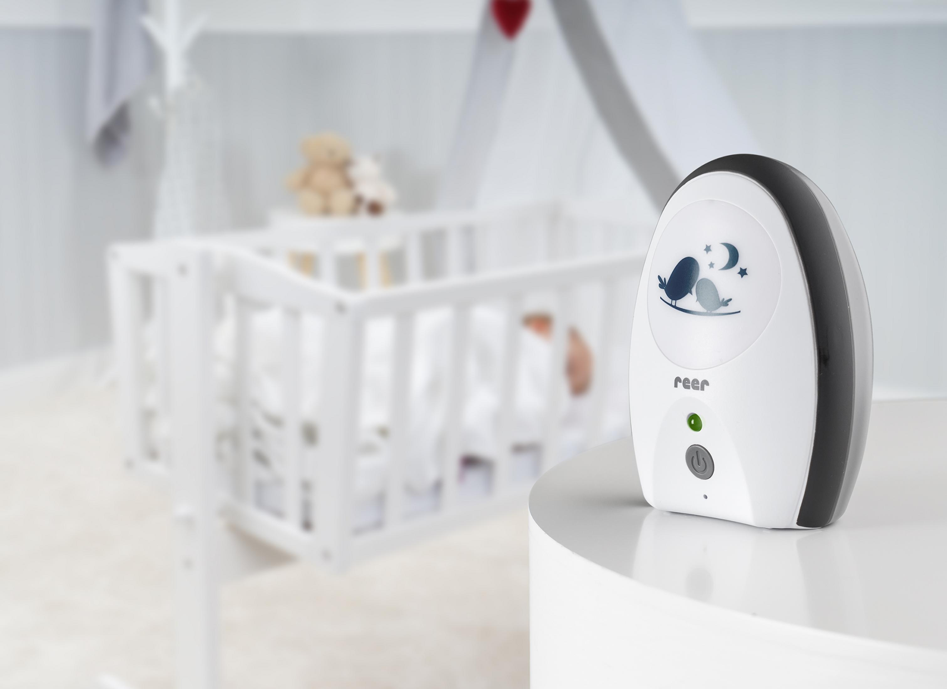 Un trasmettitore baby monitor bianco con motivo di uccelli e luna è sul tavolo.