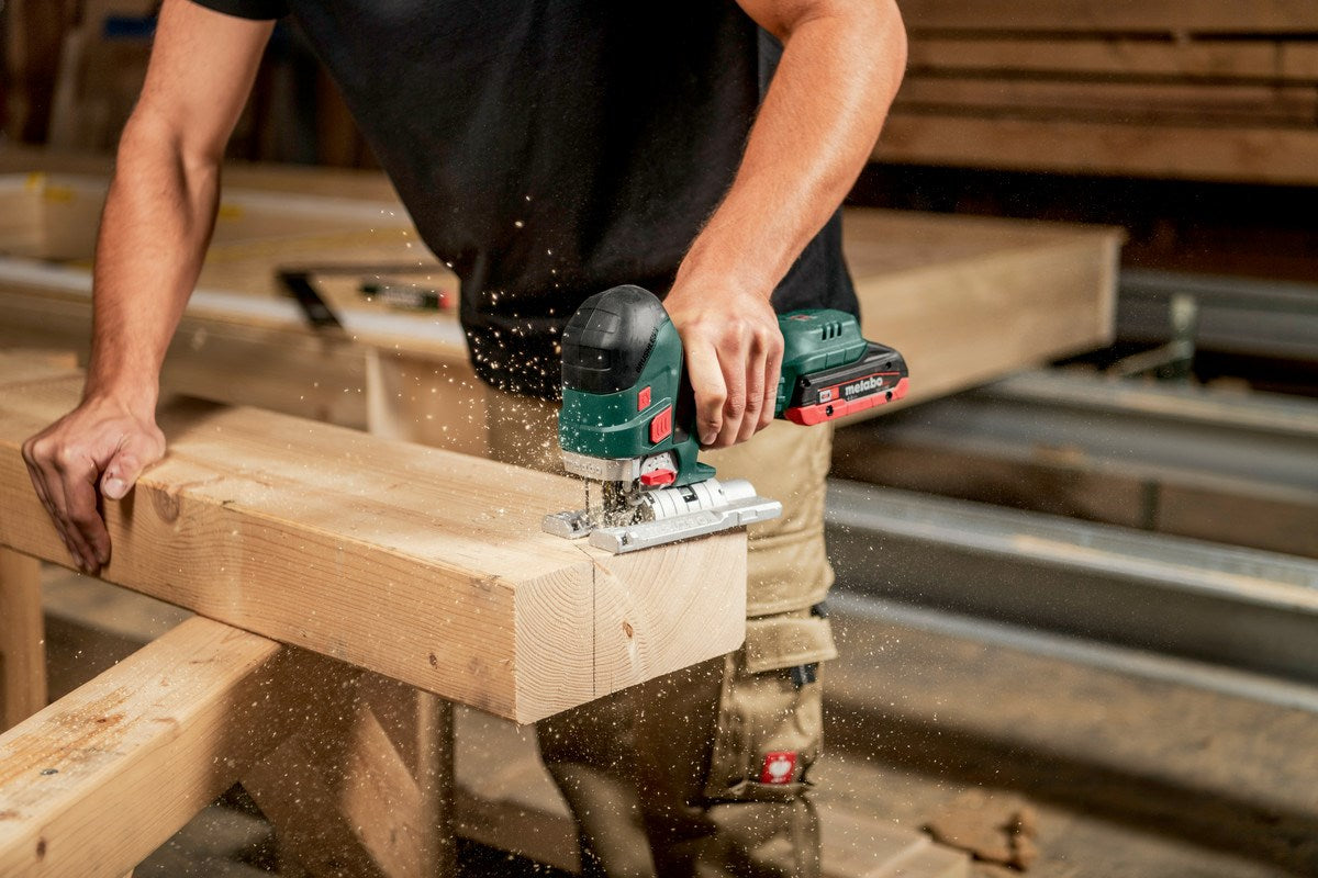 A man cuts wood with a jigsaw. Sawdust flies.