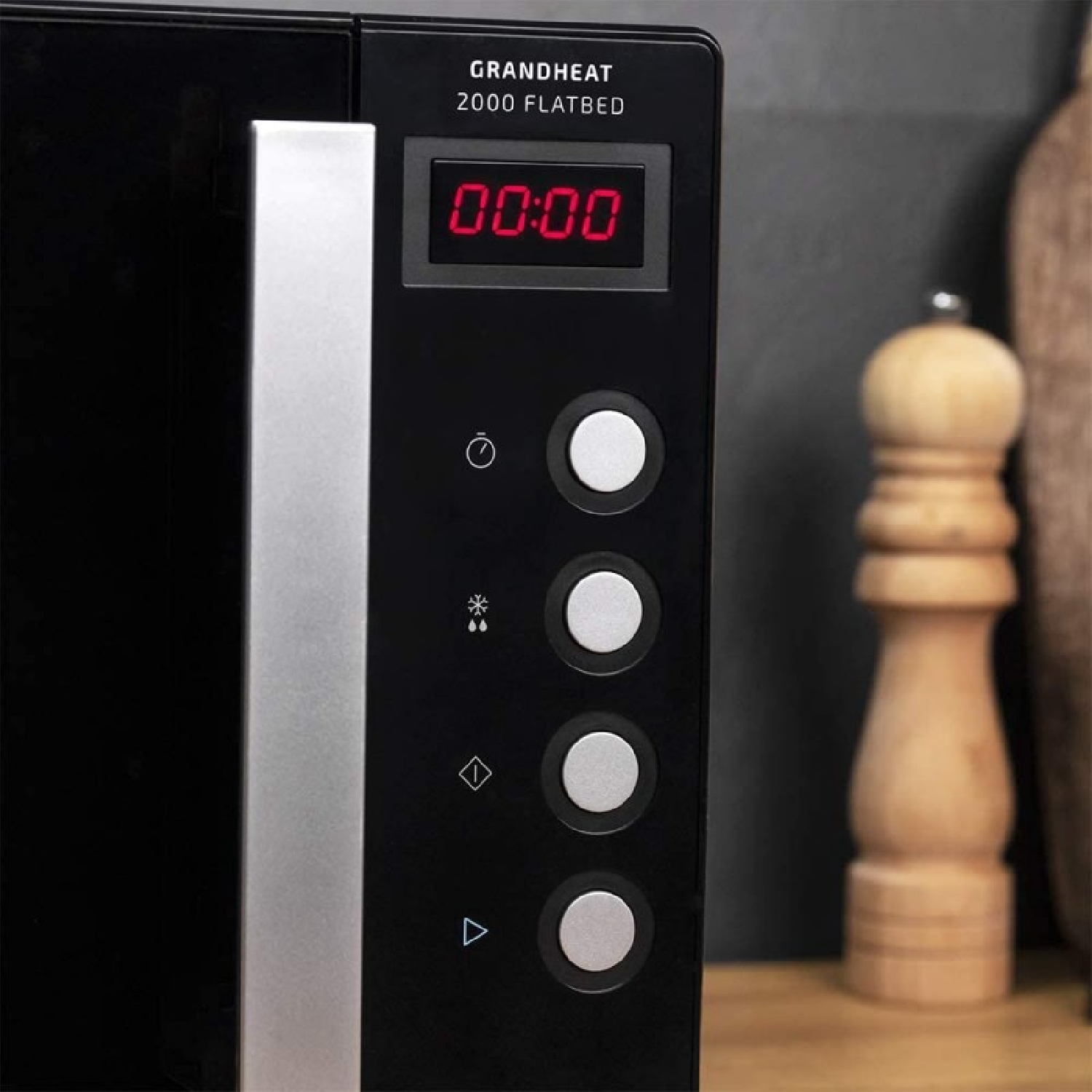 Panel de control de microondas negro con pantalla digital roja y molinillo de madera al lado.