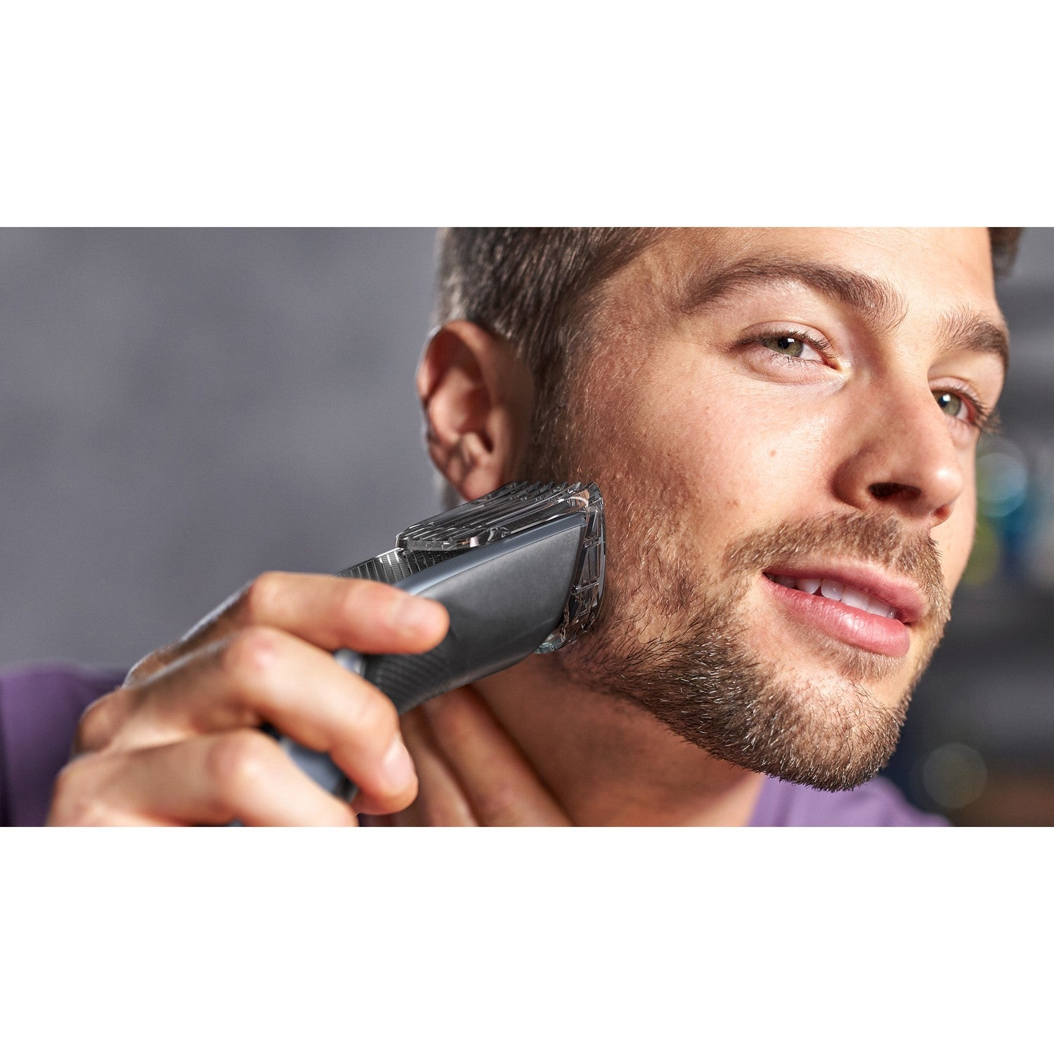 Hombre recortándose la barba con recortadora eléctrica. Primer plano de cara y manos.