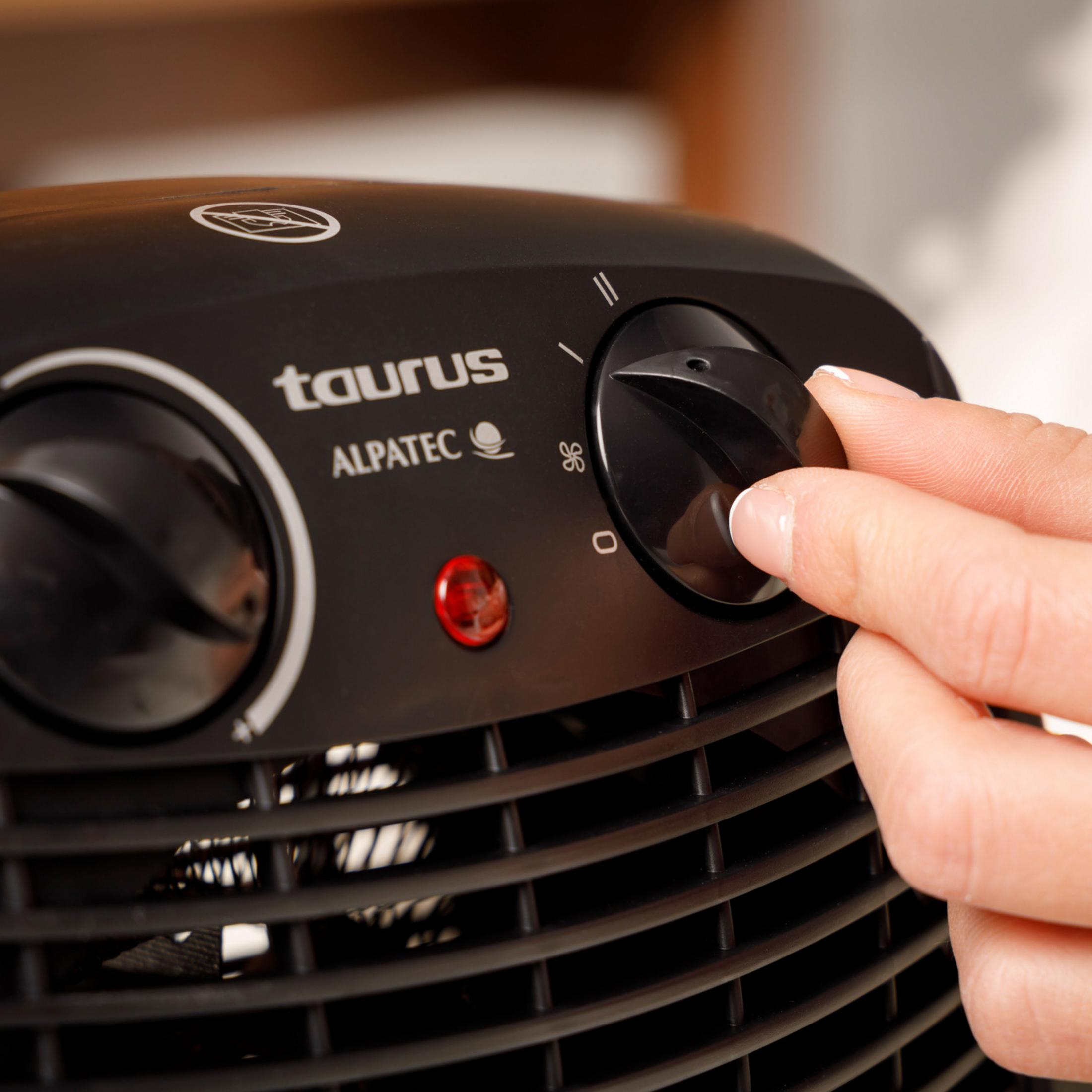 Una mano ajusta el dial de un calentador negro Taurus Alpatec con luz indicadora roja.