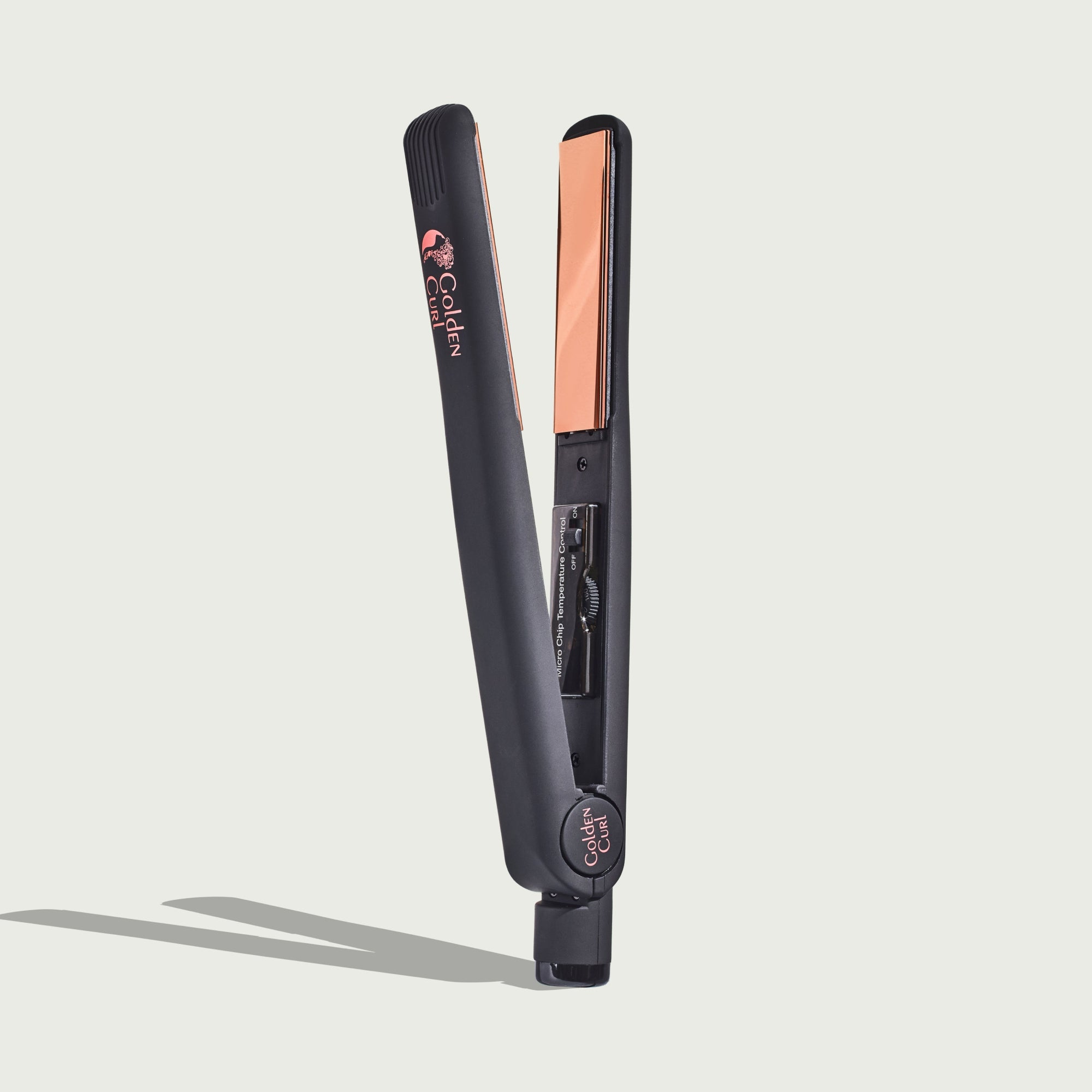 Una piastra per capelli scura e aperta con piastre color rame e logo.