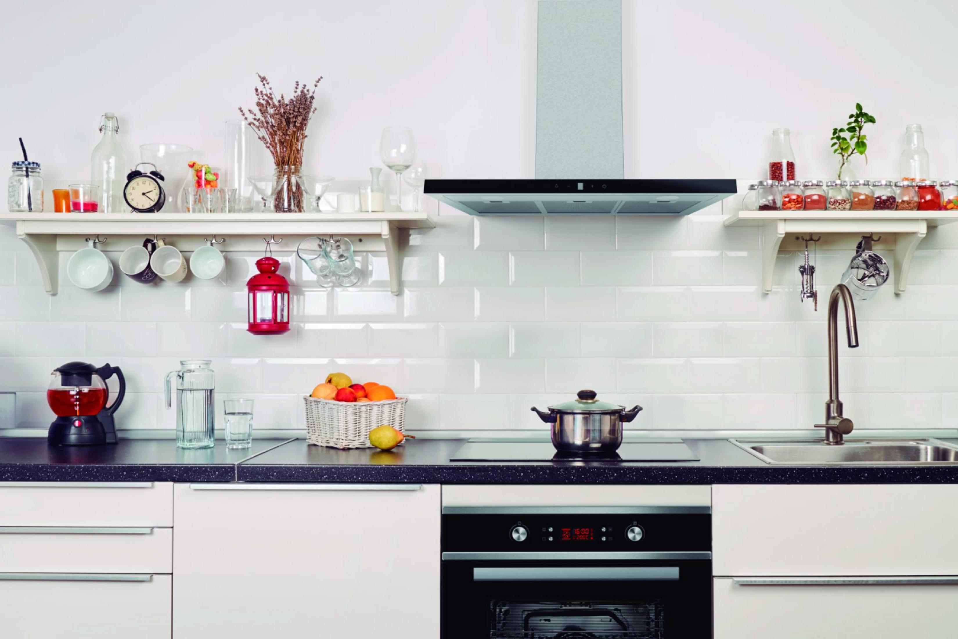 Una cocina con azulejos blancos tipo metro, estantes y electrodomésticos.