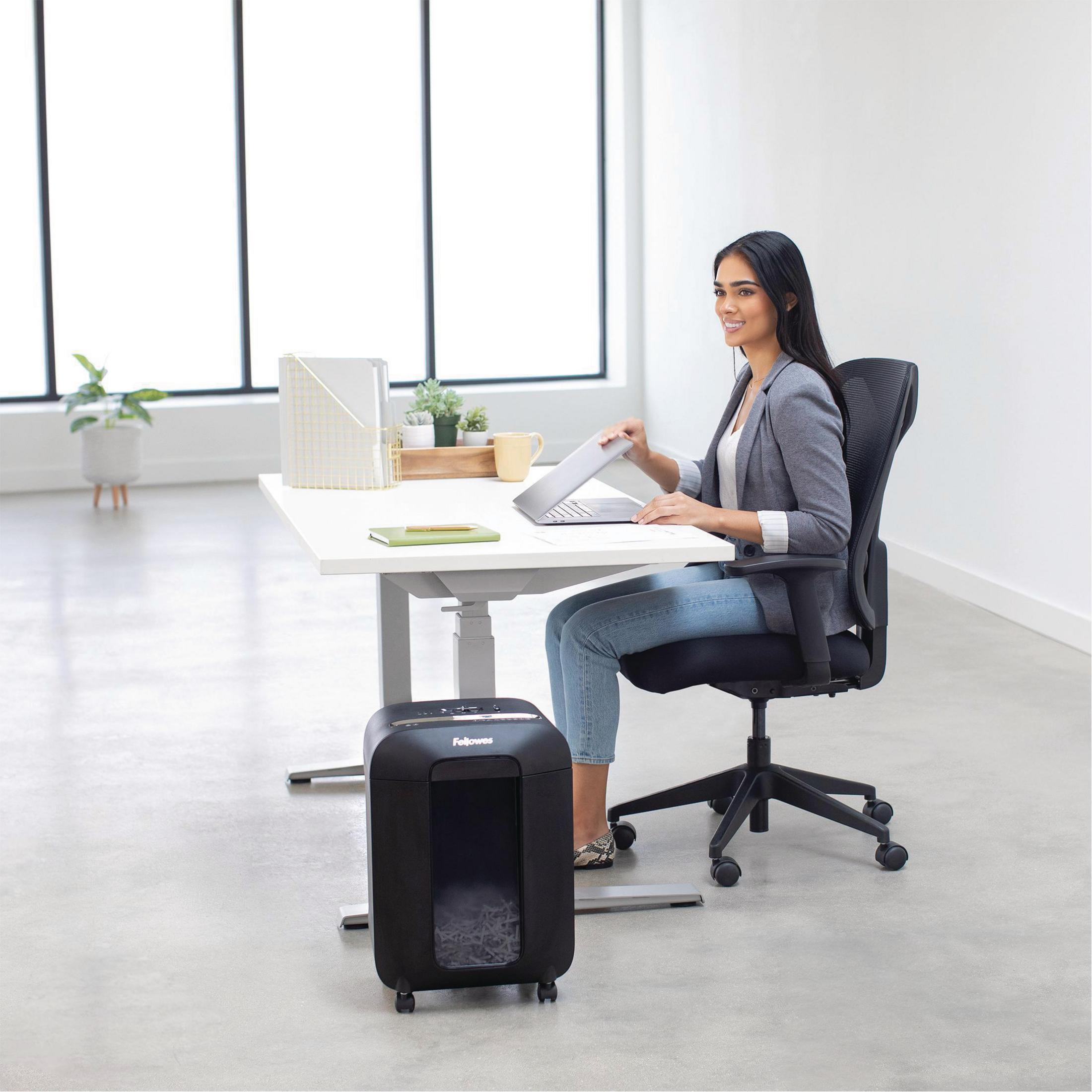 Femme à un bureau avec ordinateur portable et destructeur de papier