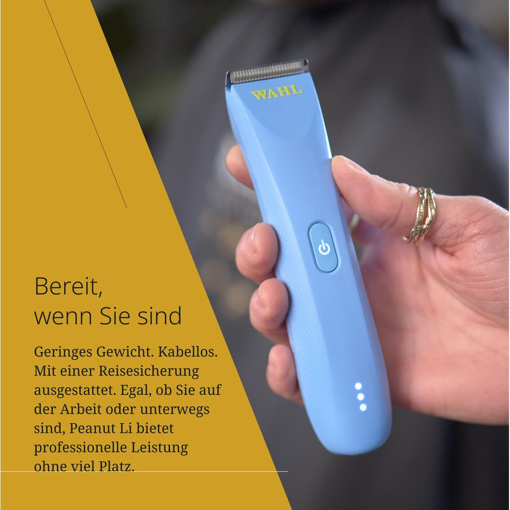Eine hellblaue Haarschneidemaschine mit WAHL-Logo wird von einer Hand gehalten.