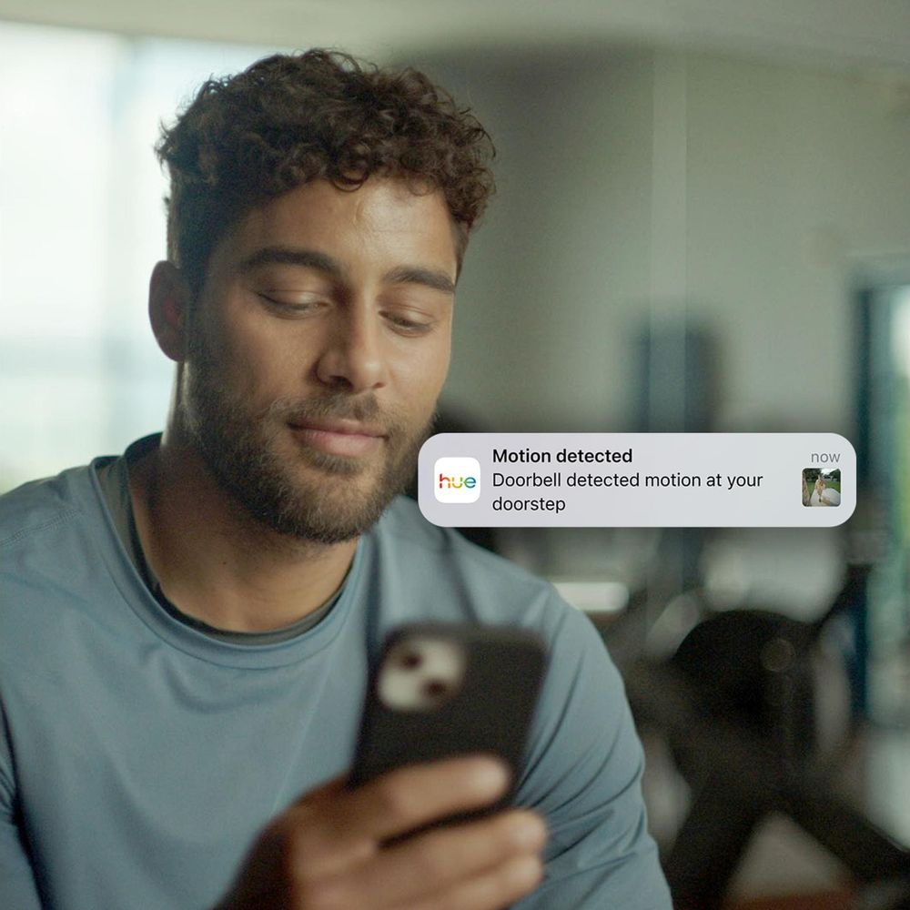 Mann schaut auf sein Handy; Benachrichtigung: Bewegung erkannt.
