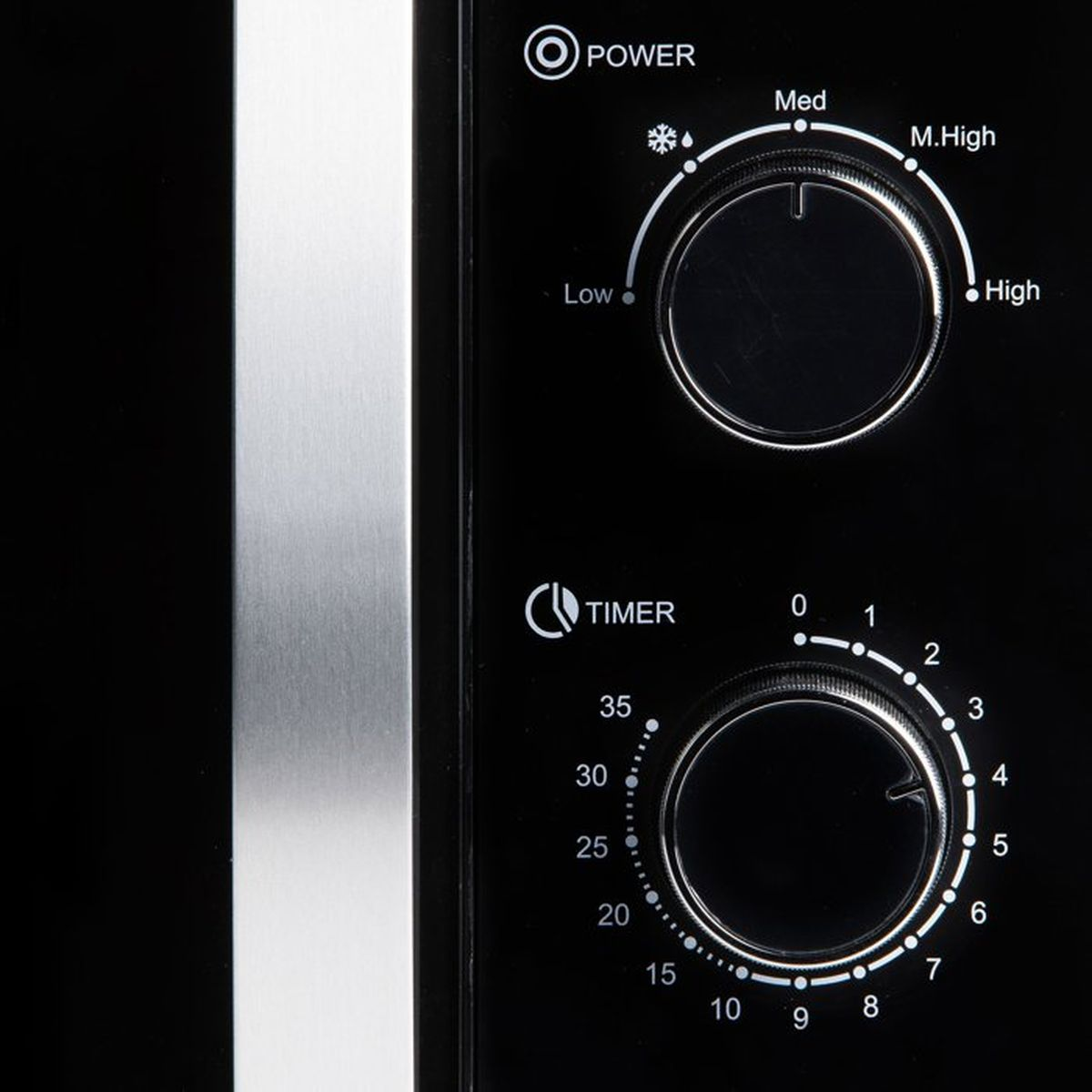 Gros plan des commandes d'un micro-ondes noir avec deux molettes.