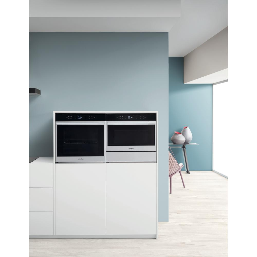 Un moderno spazio cucina con due forni da incasso, mobili bianchi e vasi decorativi.
