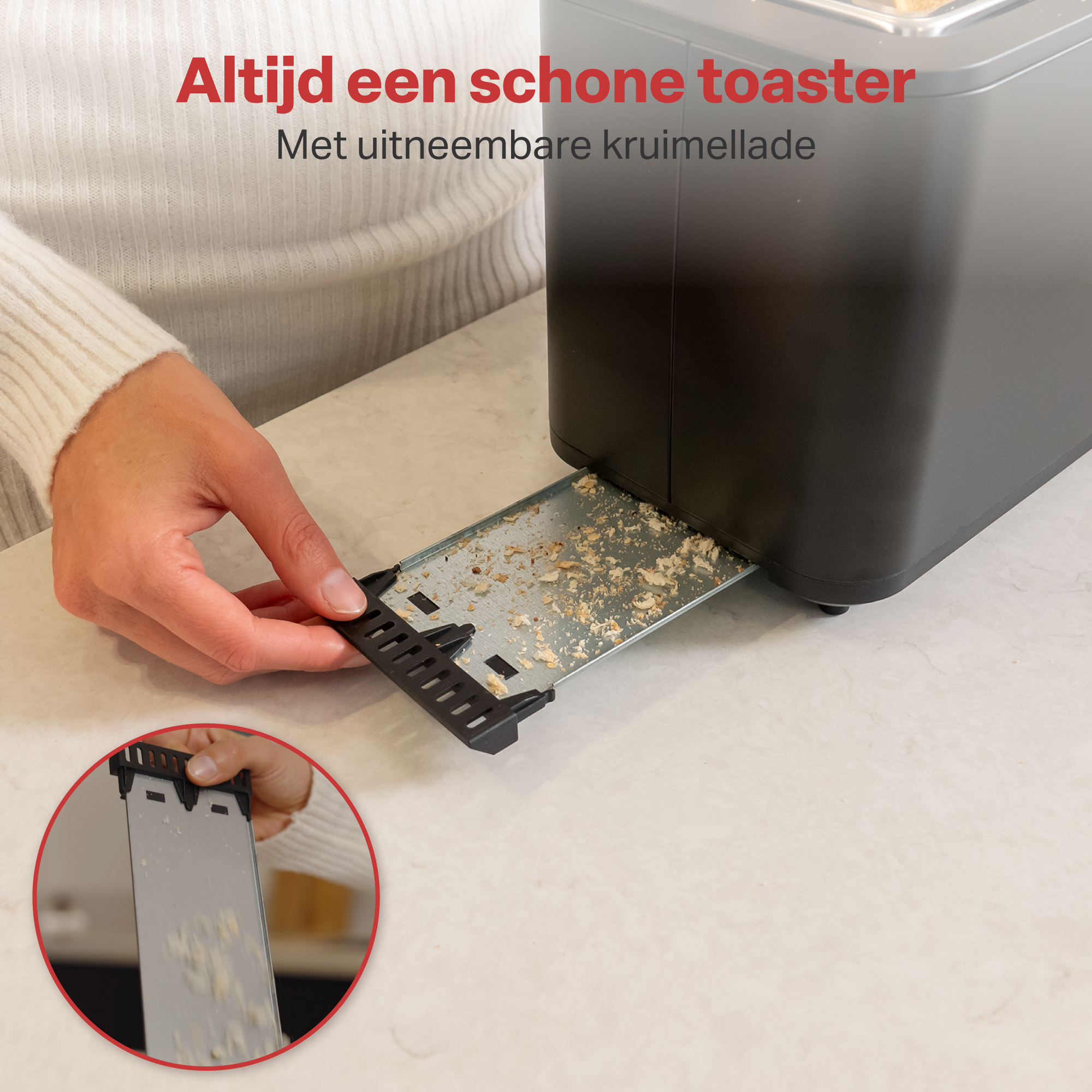 Een hand trekt een kruimellade uit een broodrooster. Kruimels zijn zichtbaar.