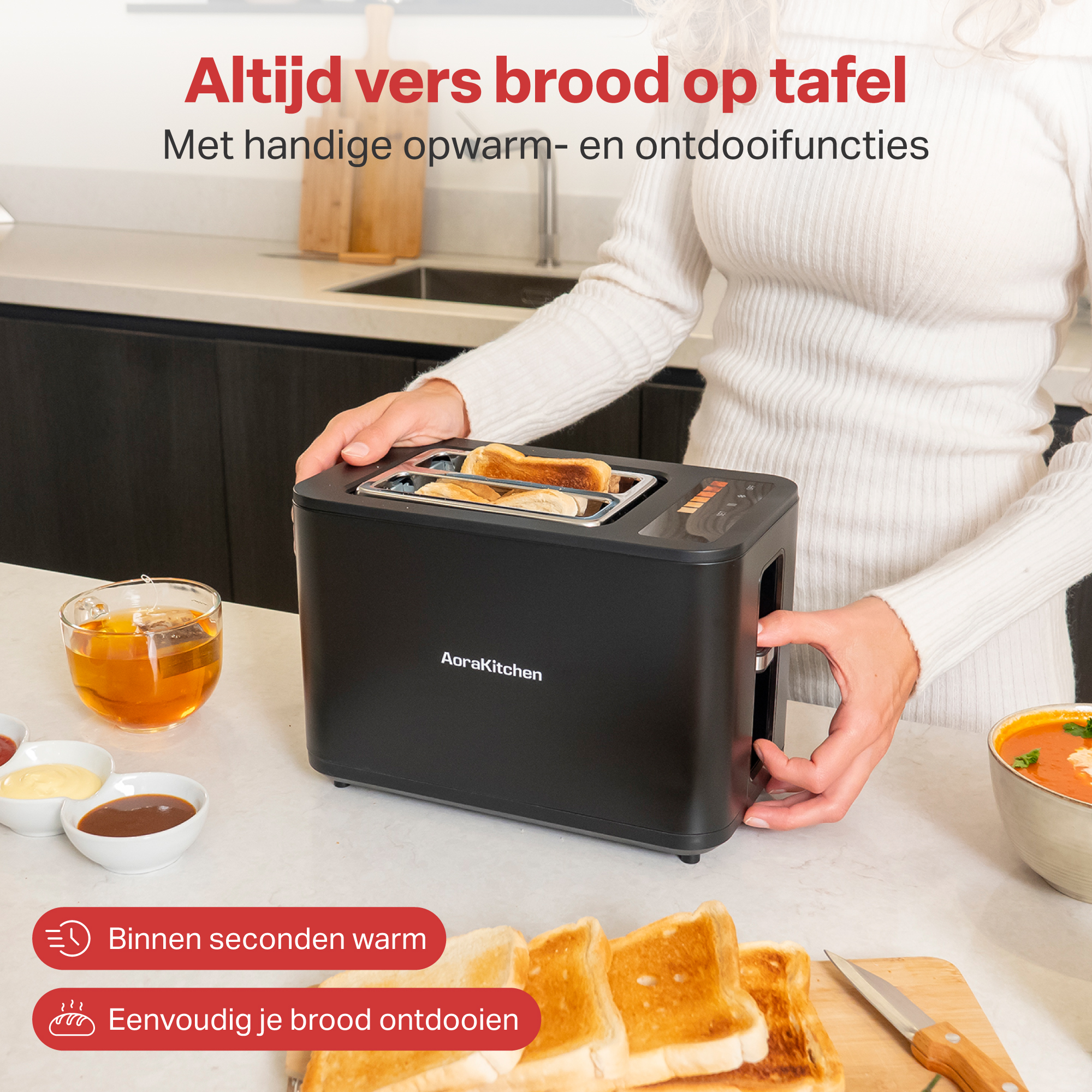 Zwarte broodrooster met toast, een kop thee en bakjes saus op een aanrecht.
