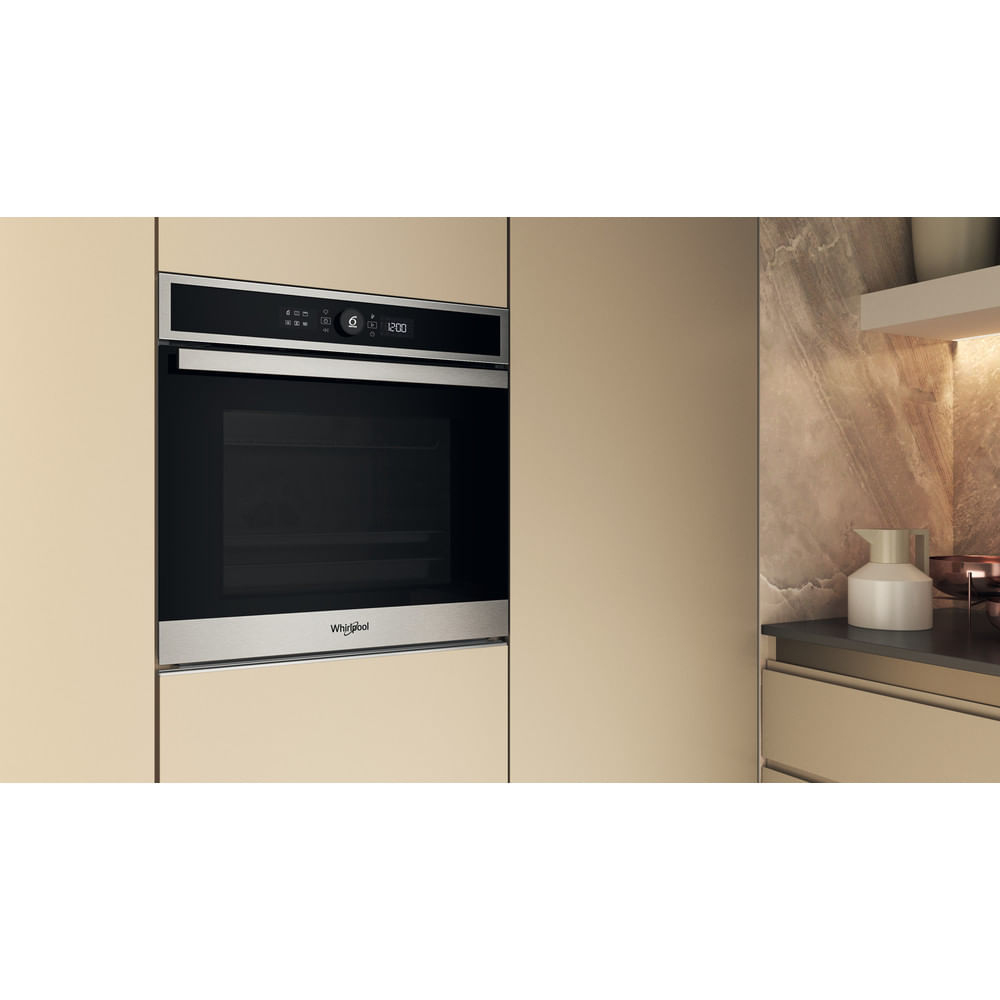 Un forno da incasso moderno in mobili da cucina beige con dettagli in acciaio inox.