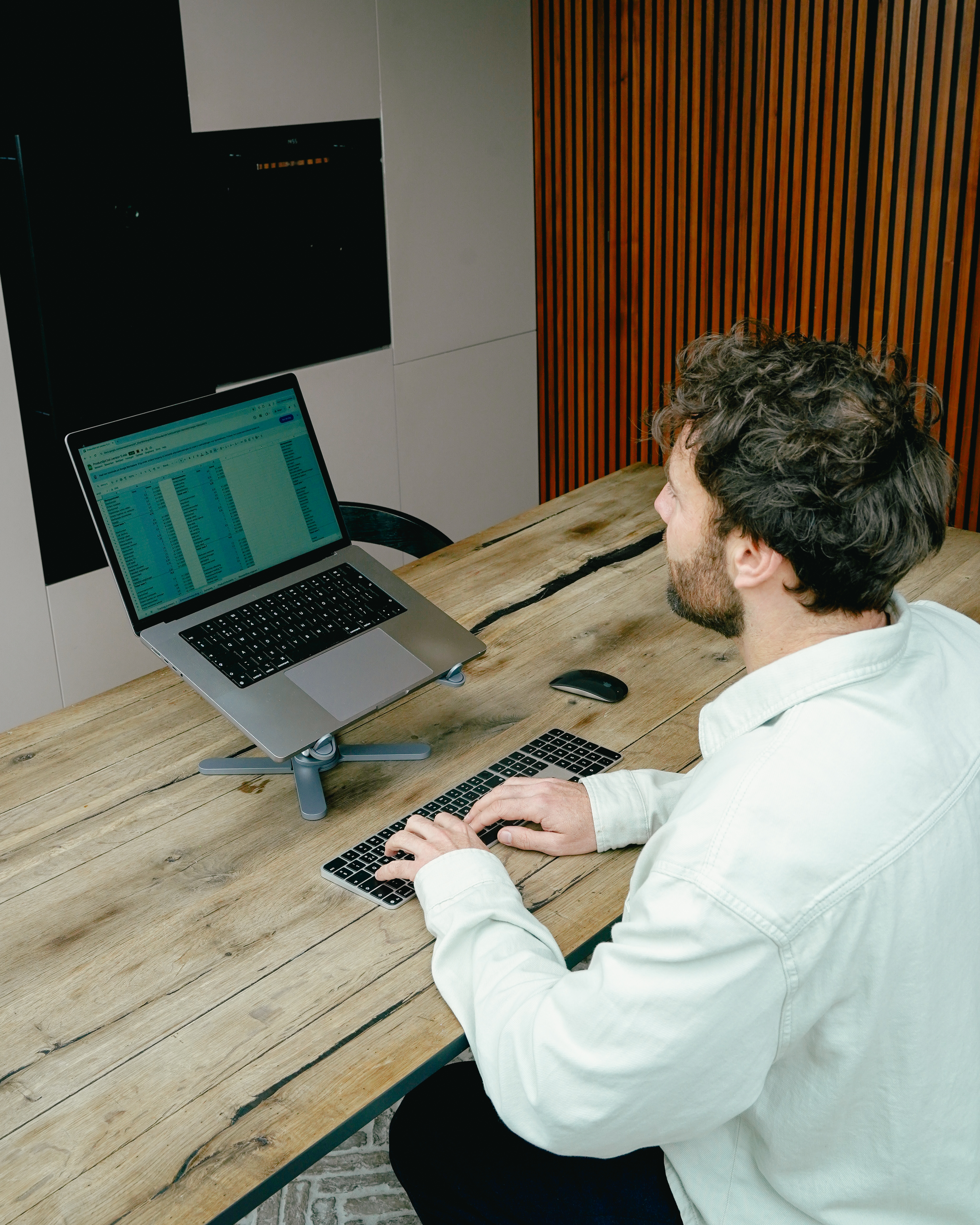 Homme tapant sur clavier devant ordinateur portable sur table en bois. Décor de cuisine.