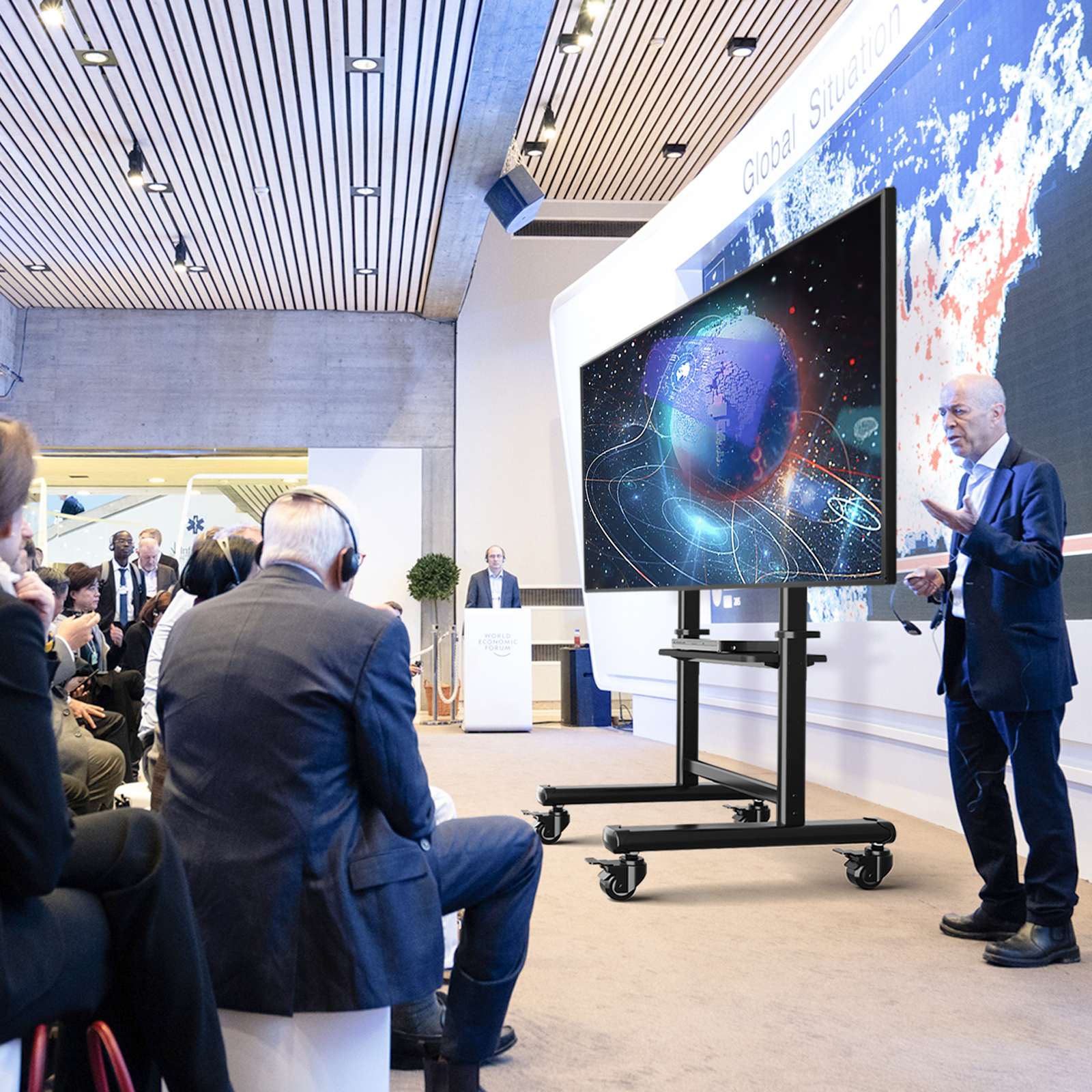 Ein Mann in einem dunklen Anzug spricht zu einem Publikum in einem Konferenzraum.
