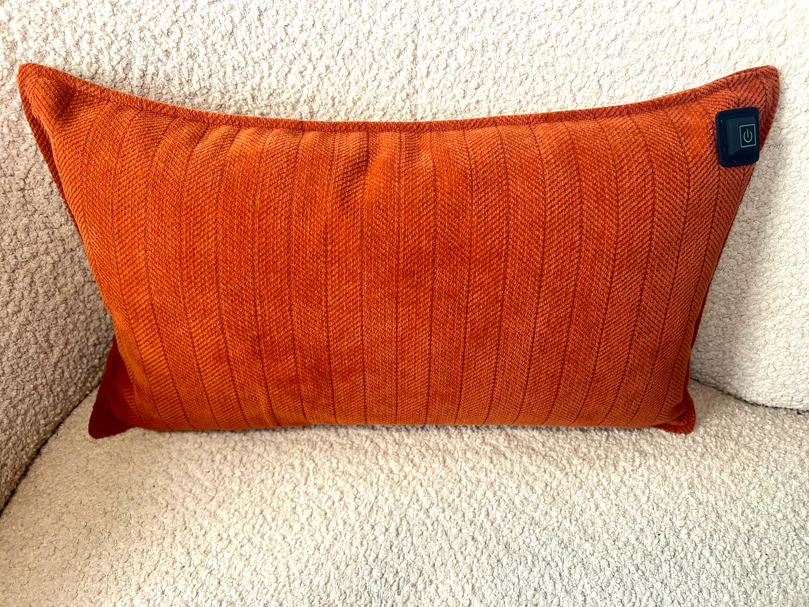 Orange Kissen mit Zickzackmuster und einem Power-Symbol-Knopf