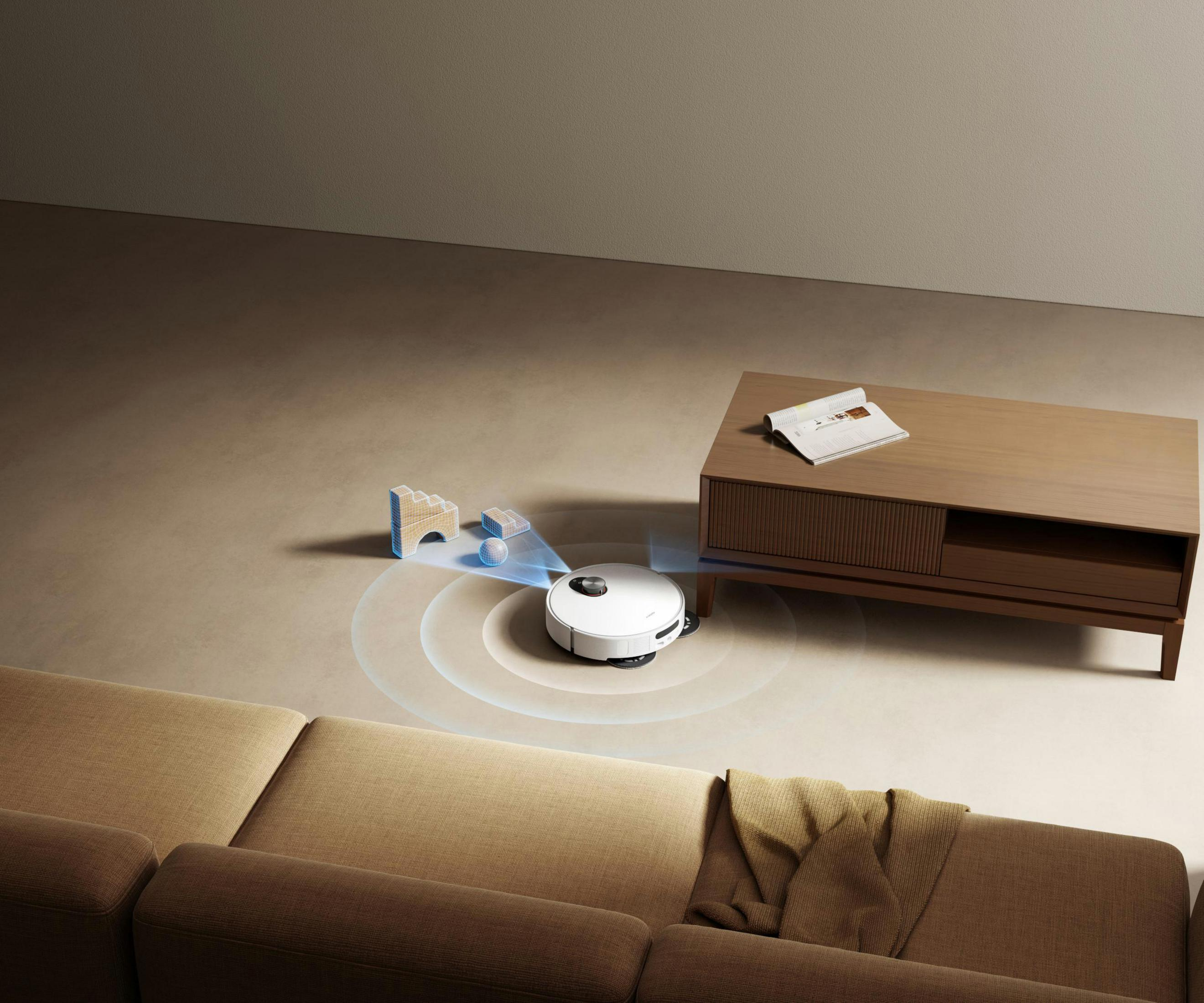 A white robot vacuum cleans a carpeted floor near a sofa and coffee table.
