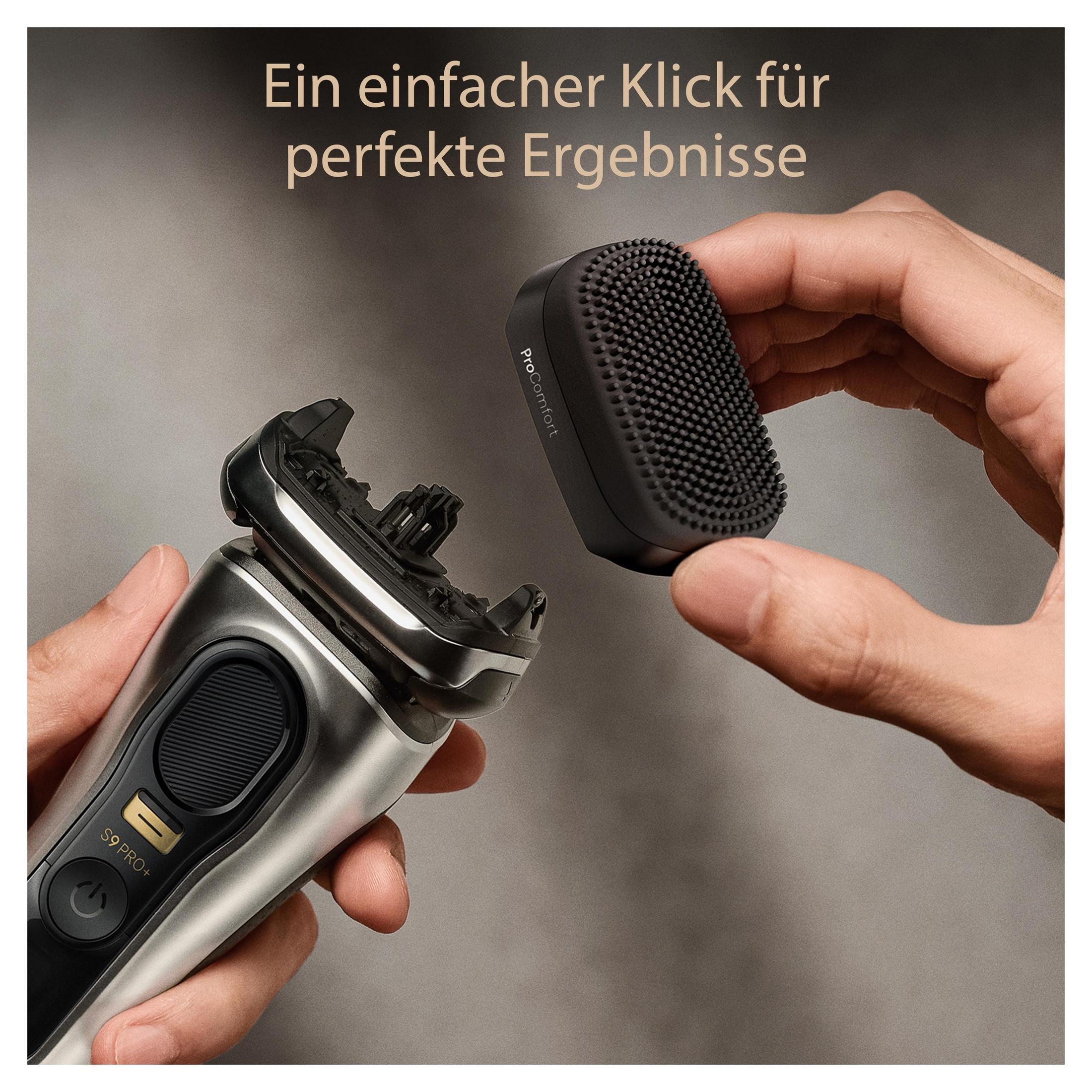 Ein Mann hält einen Elektrorasierer und einen Aufsatz mit Borsten.