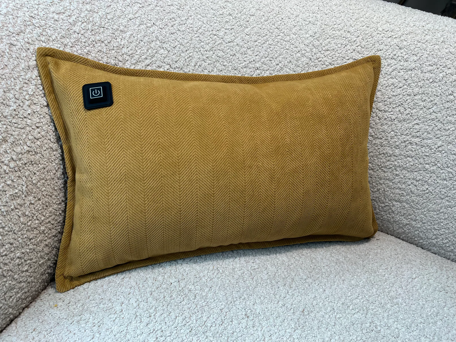 Ein gelbes Kissen mit Fischgrätenmuster und einem schwarzen Power-Button-Symbol.