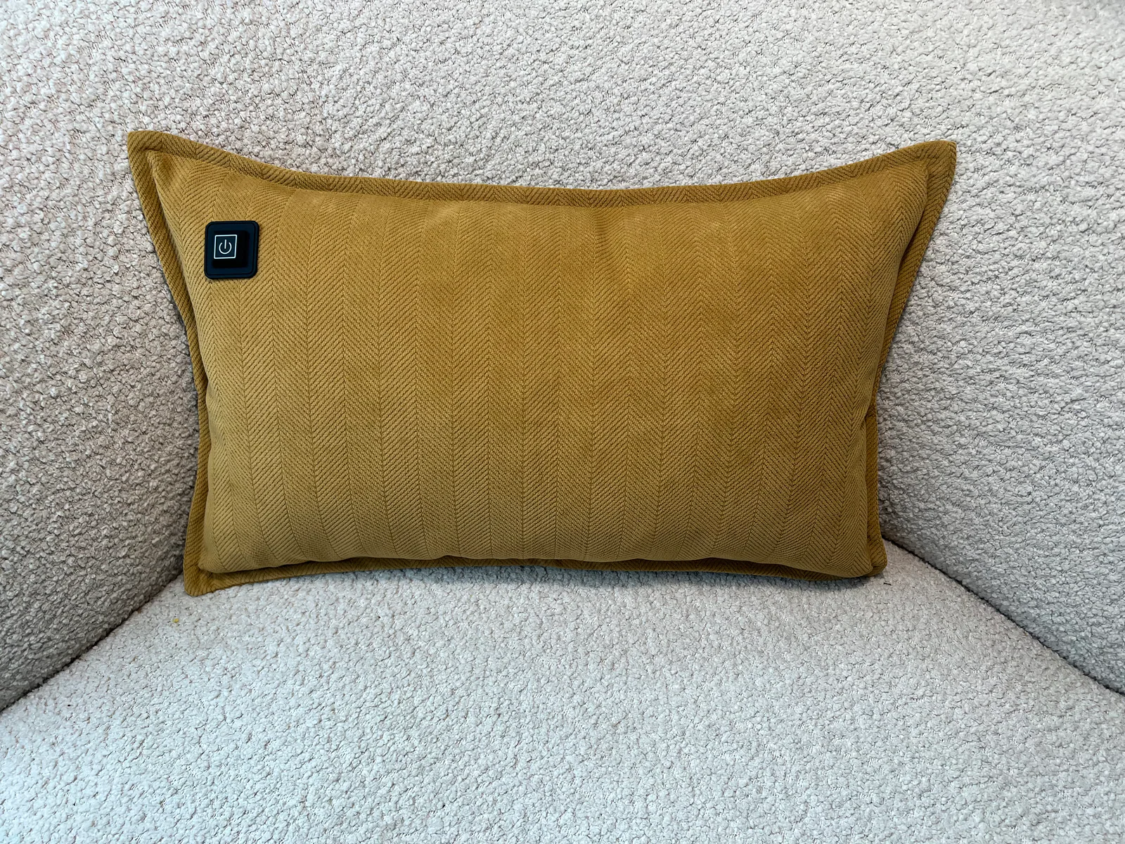 Ein gelbes Kissen mit einem Power-Symbol auf einem hellen Sofa.