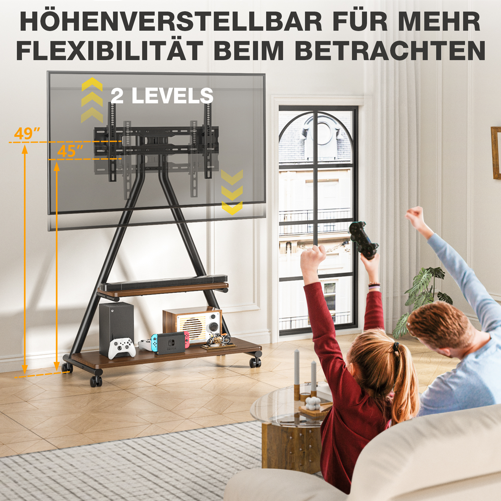Ein TV-Ständer mit Spielekonsolen und ein Vater mit Kind jubeln vor einem Fenster.