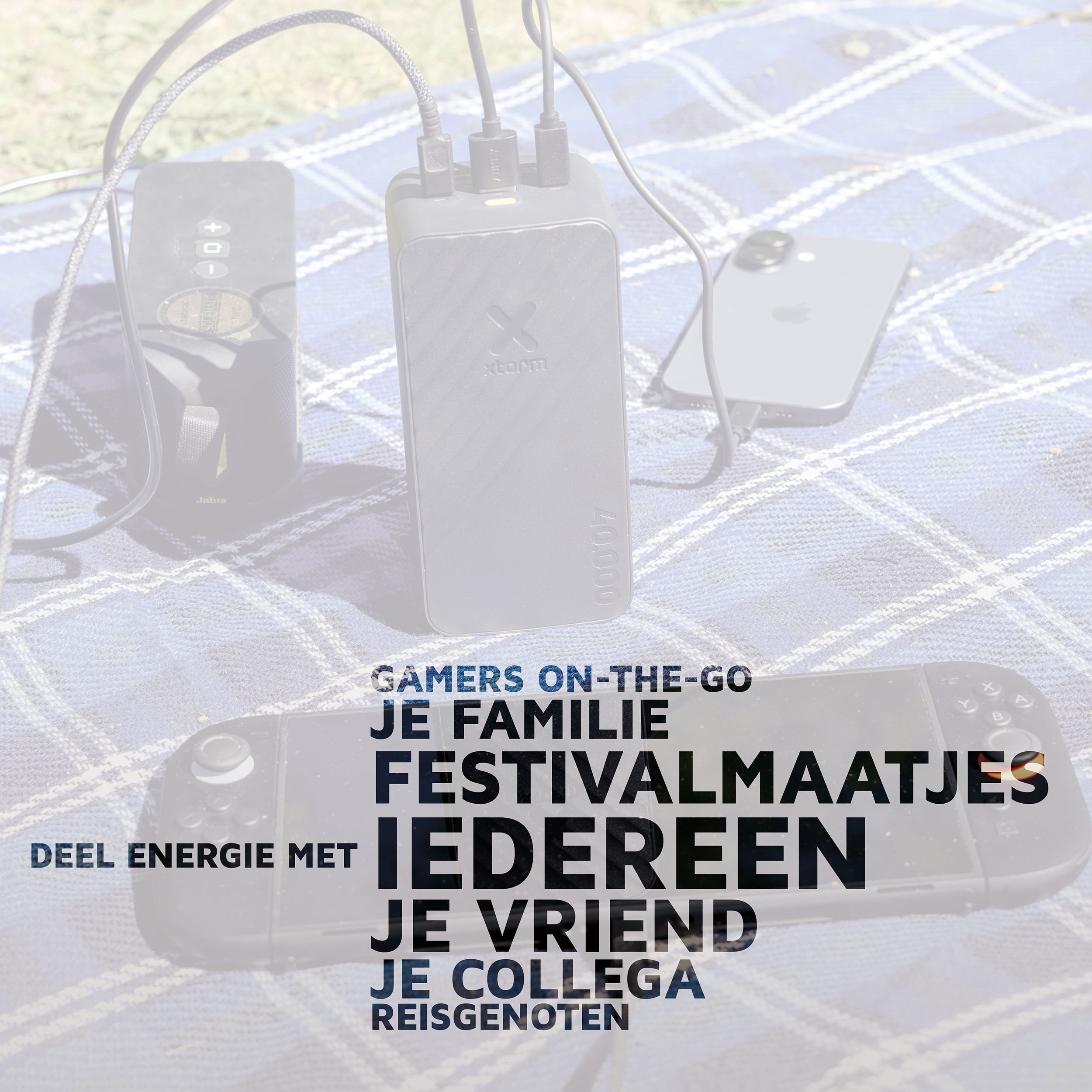 Powerbank, Lautsprecher, Smartphone und Spielekonsole auf karierter Decke.