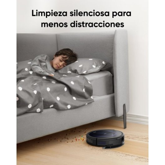 Un niño duerme en la cama mientras un robot aspirador limpia el suelo.
