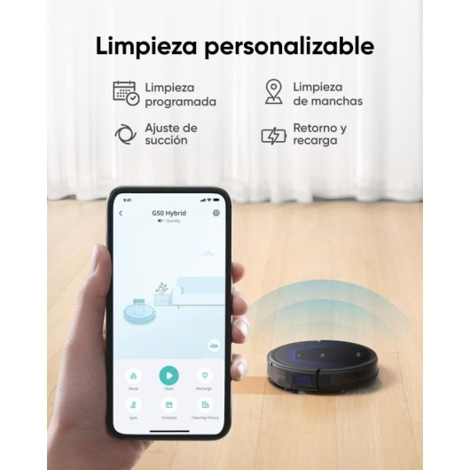 Un smartphone muestra una app que controla un robot aspirador. El robot está a su lado.