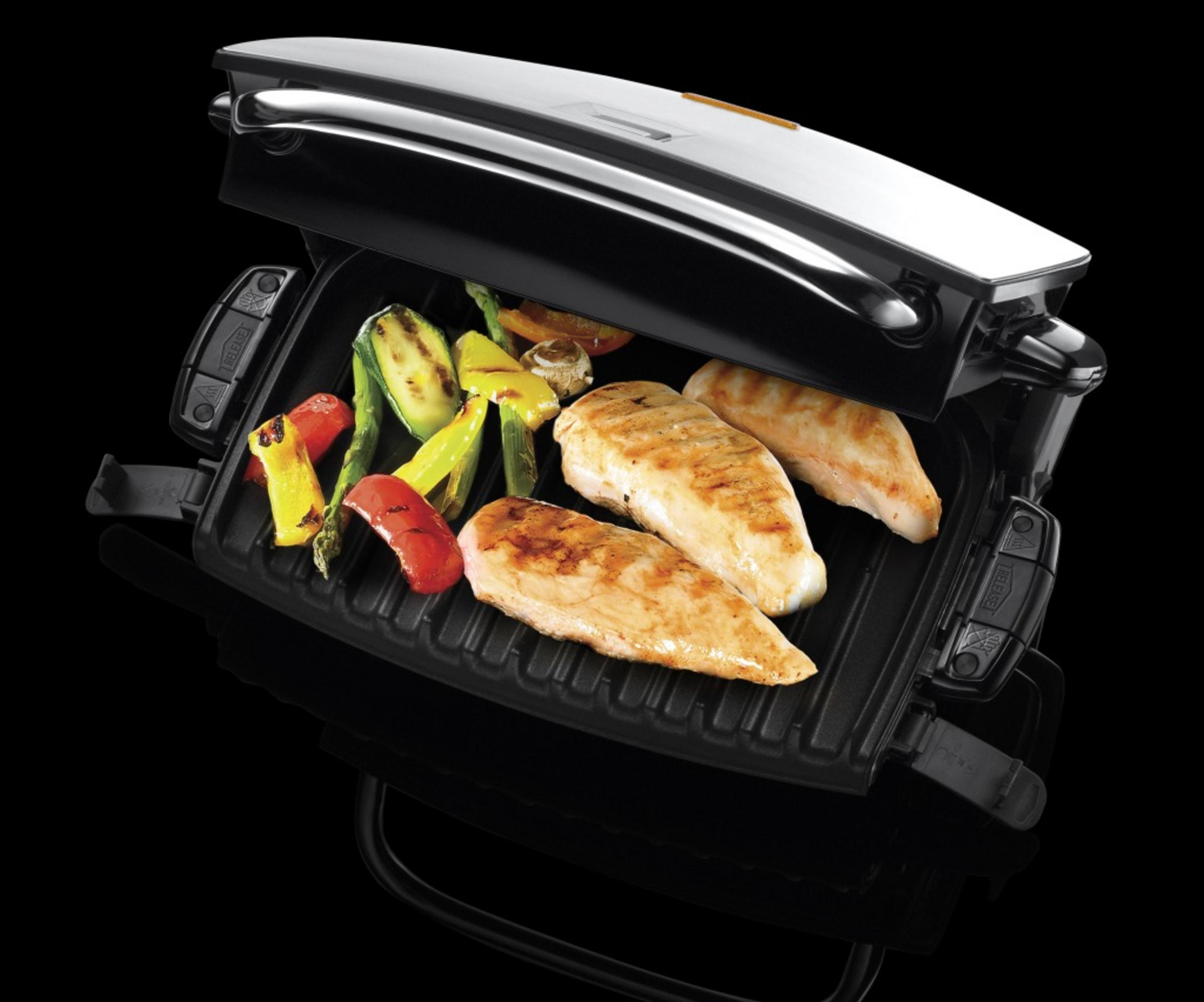 Gegrillte Hähnchenbrust und Gemüse auf einem schwarzen Kontaktgrill mit geschlossenem Deckel.