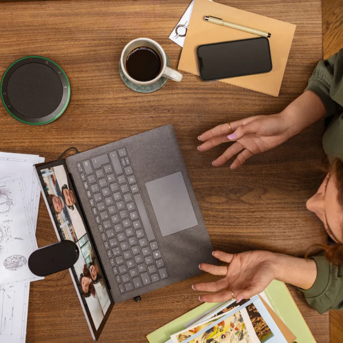 Eine Frau liegt auf einem Holztisch mit einem Laptop, einer Kaffeetasse und einem Telefon.