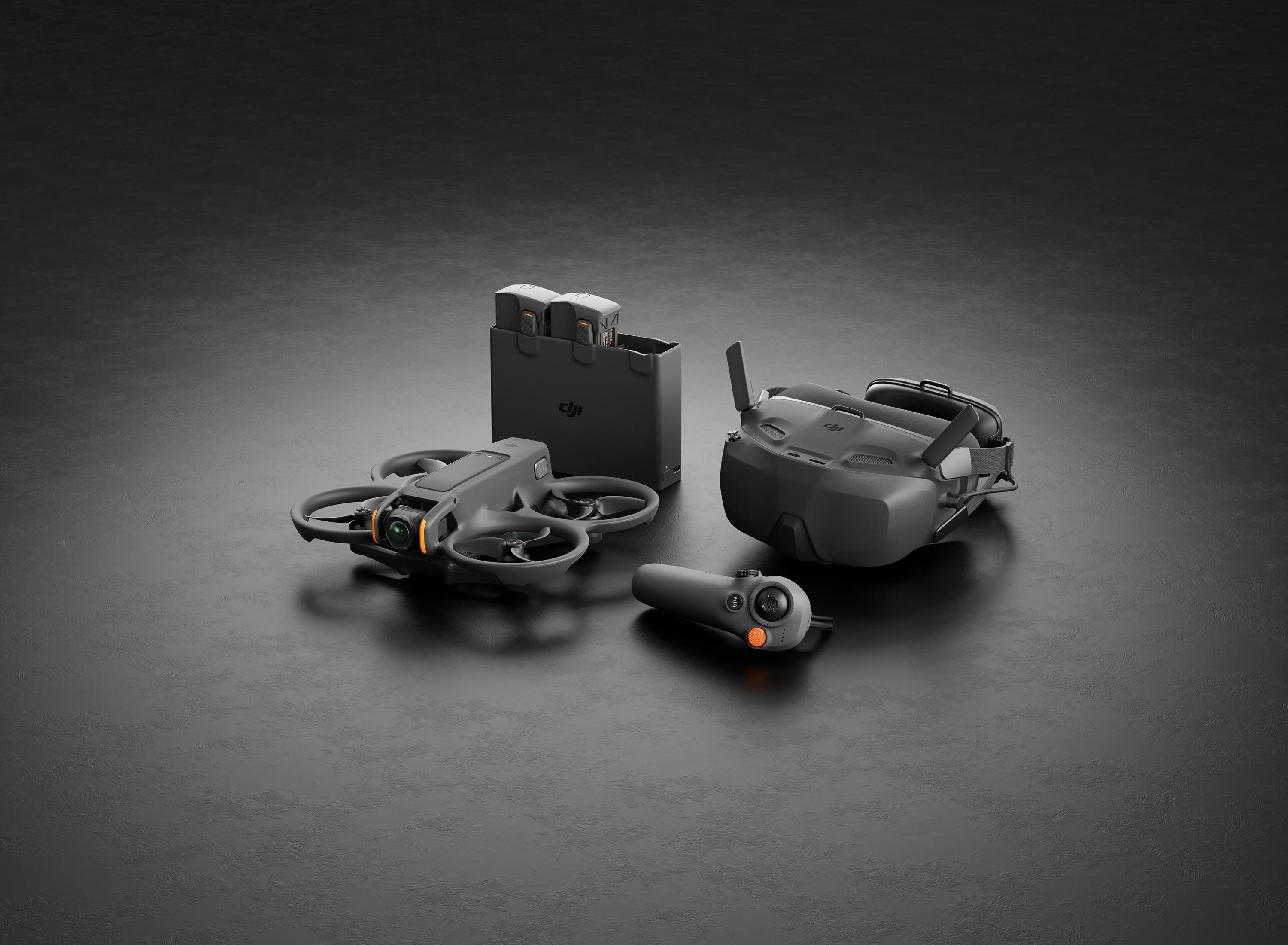 Grauer Drone, Controller, Brille und Akkus auf dunklem Grund.