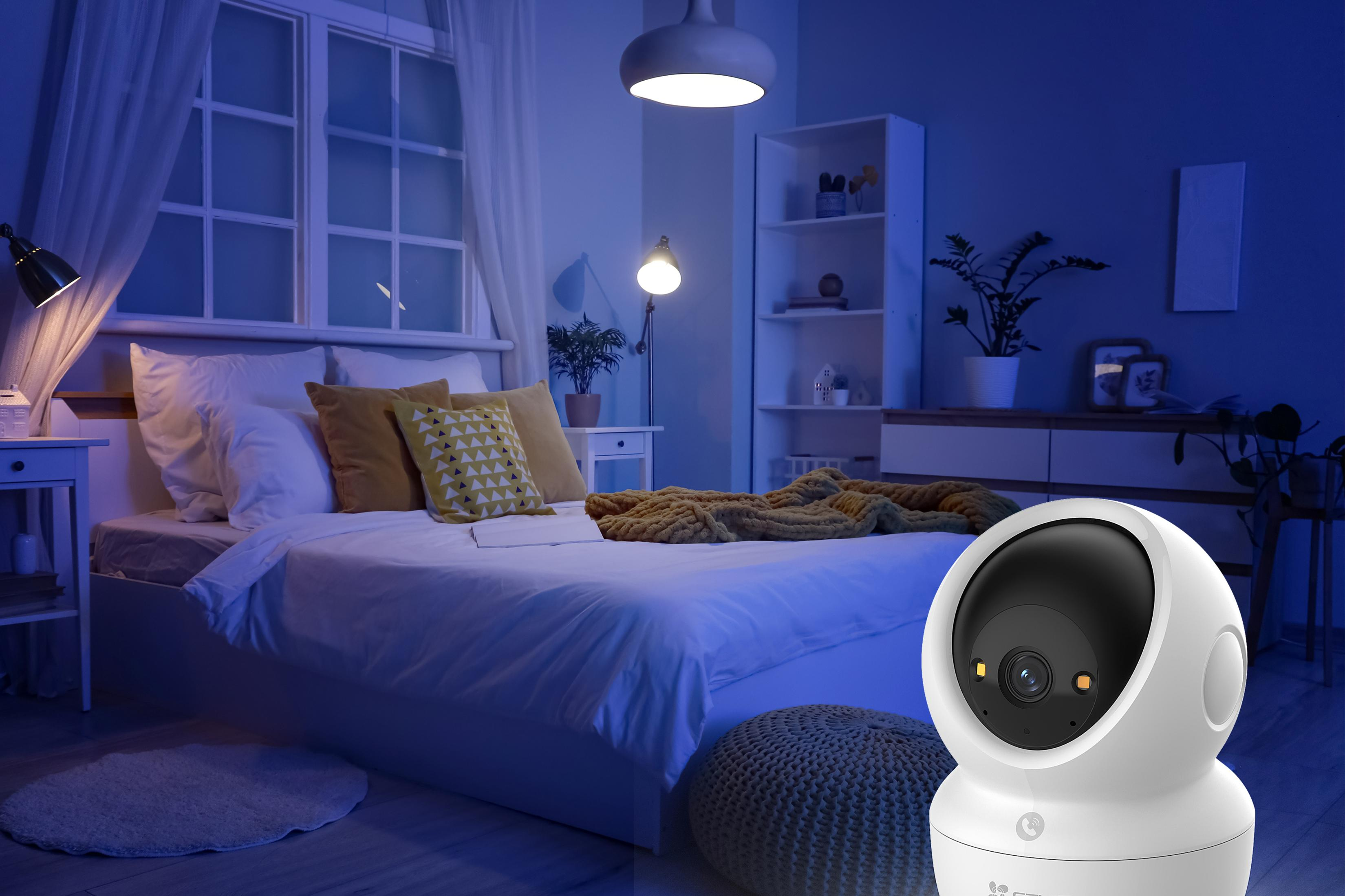 Una telecamera di sicurezza bianca è in primo piano in una camera da letto di notte.