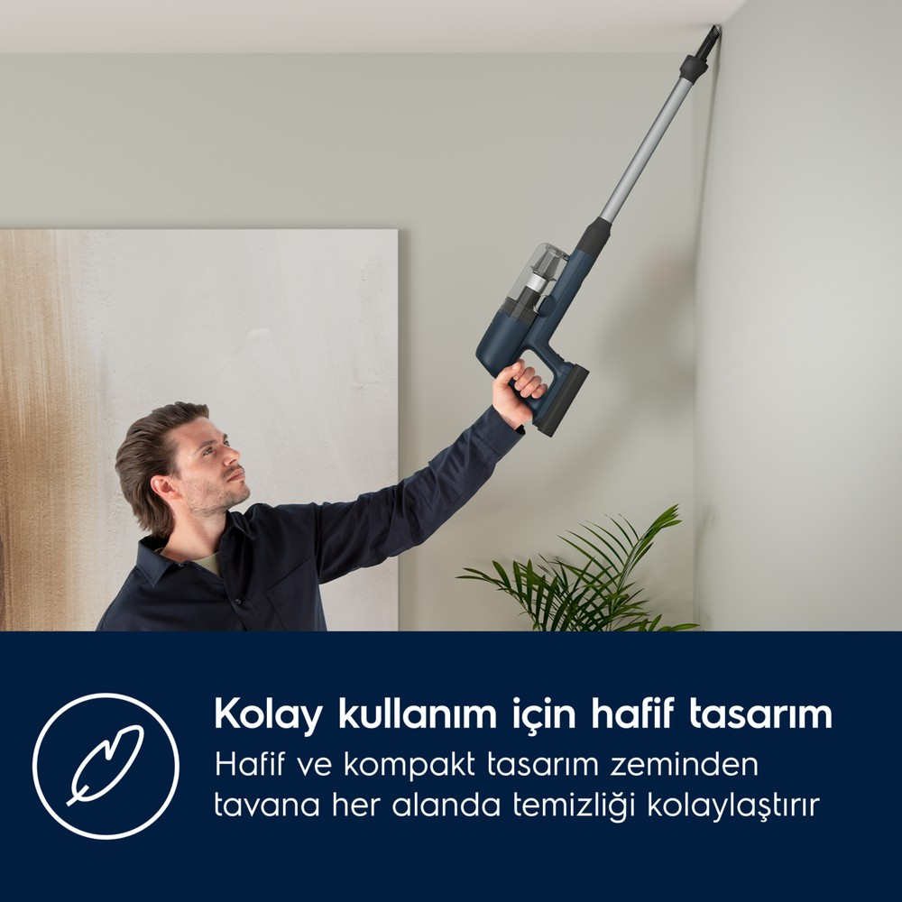 Mann reinigt die Ecke oben mit einem blauen Handstaubsauger.